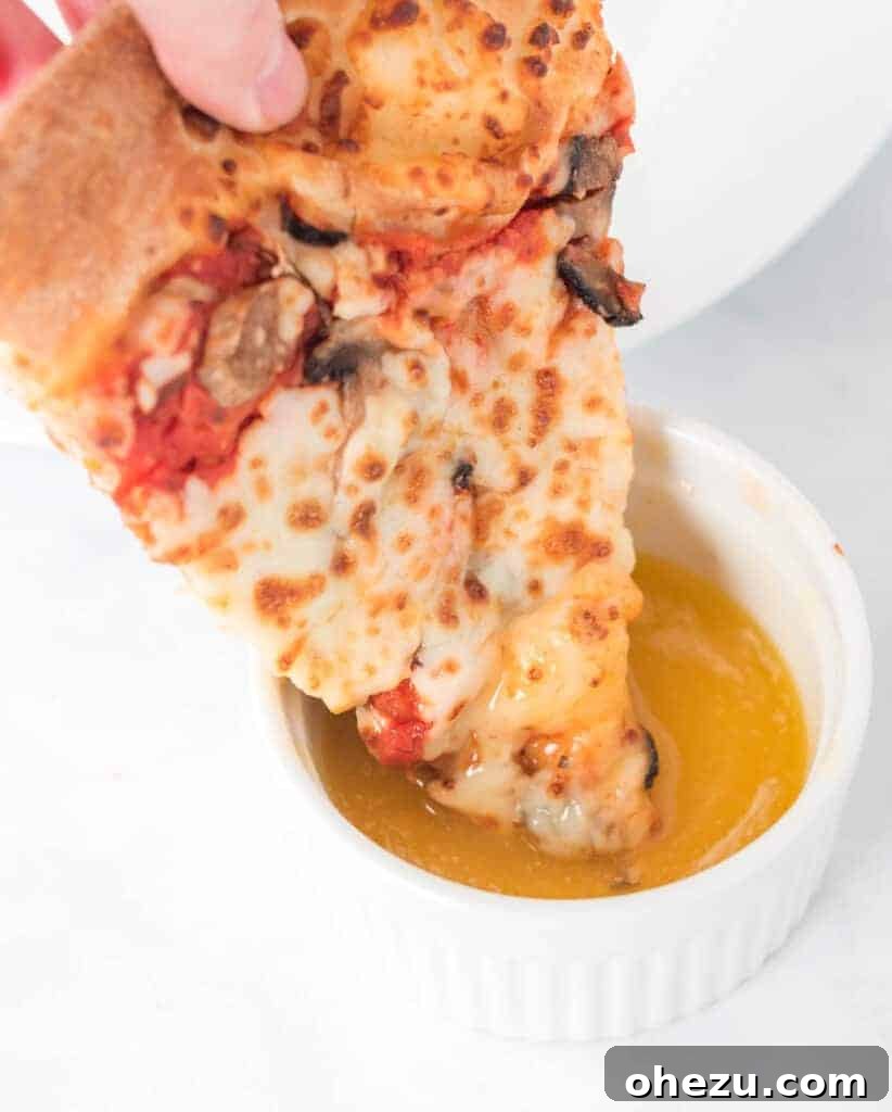 A slice of pepperoni pizza being generously dipped into a ramekin of homemade garlic sauce.