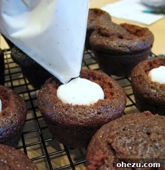 A cupcake with its top removed in a cone shape, ready for cream filling.
