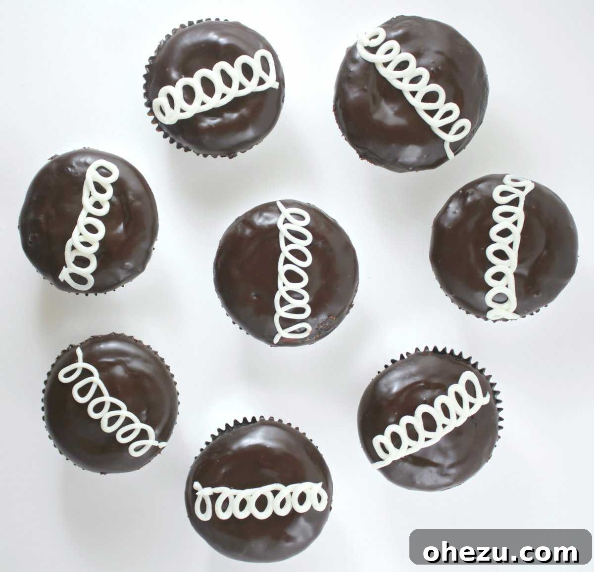 A stunning display of finished Hostess-style cupcakes, showing off their perfect ganache and signature vanilla swirl.