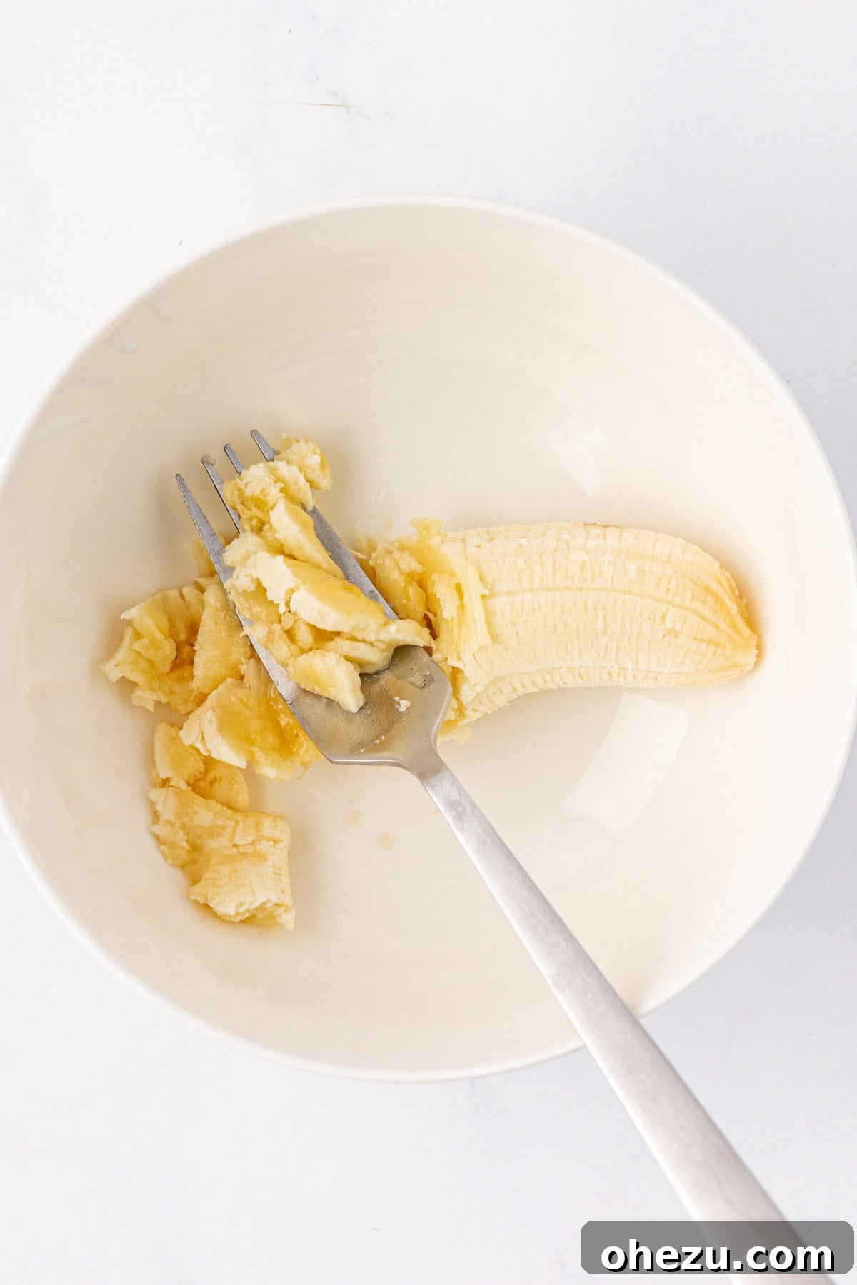 mashing a banana in a bowl with a fork