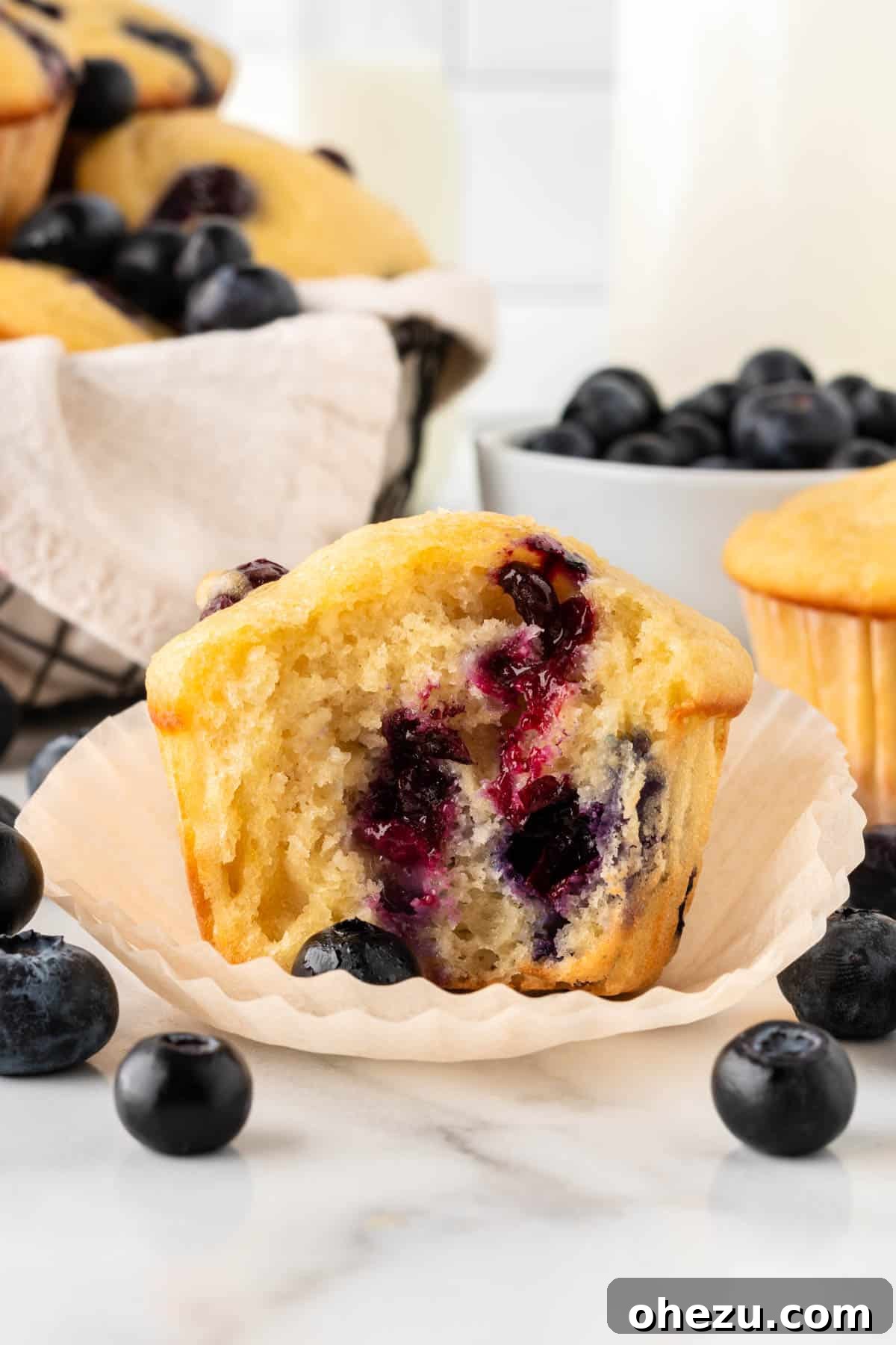 Moist Greek Yogurt Blueberry Muffins 16 Cross-section of a Greek yogurt muffin with a bite taken out, revealing its fluffy interior and evenly distributed fresh blueberries.
