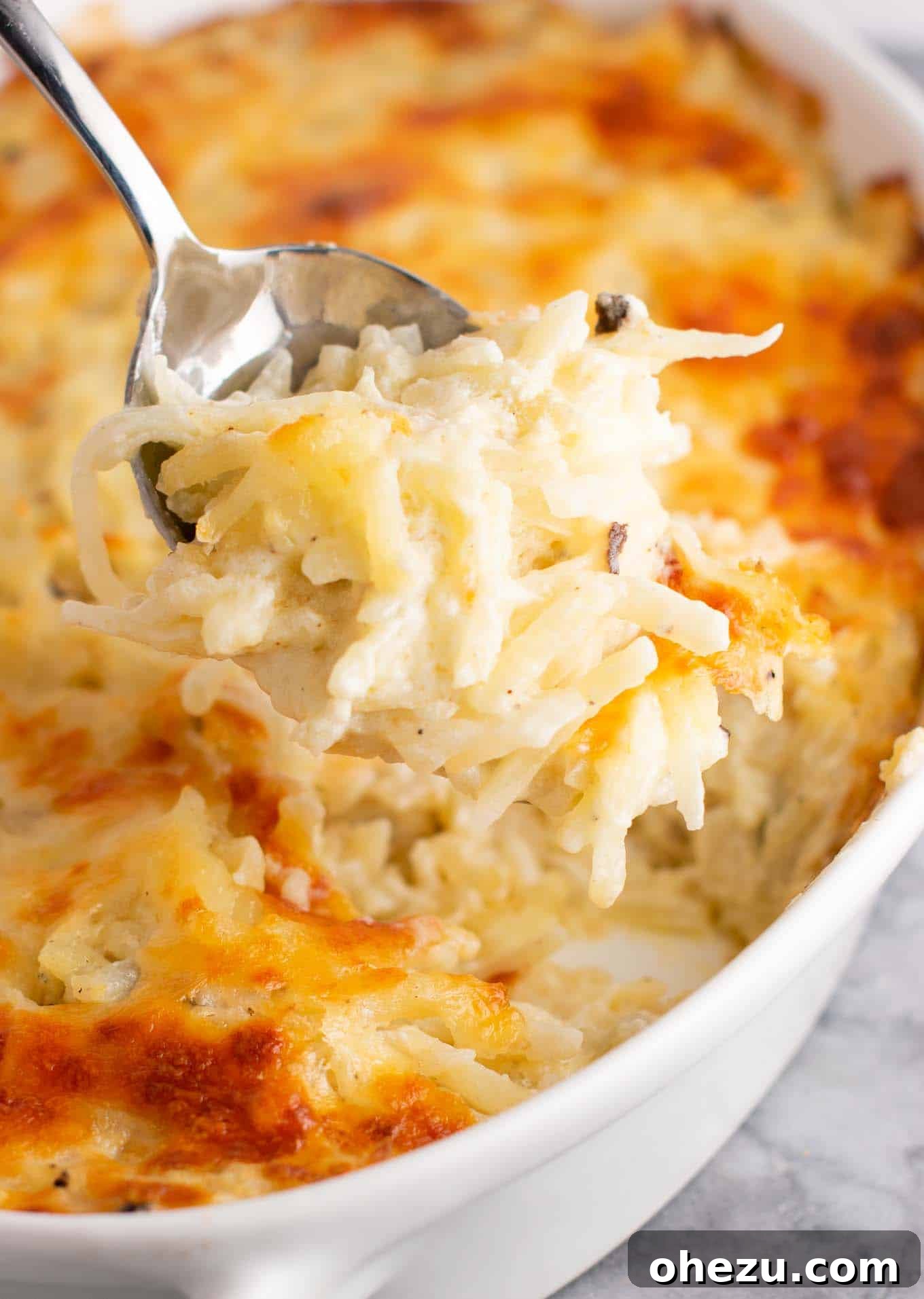 Close-up of a serving of vegetarian hash brown casserole, highlighting the creamy, cheesy interior and crispy edges