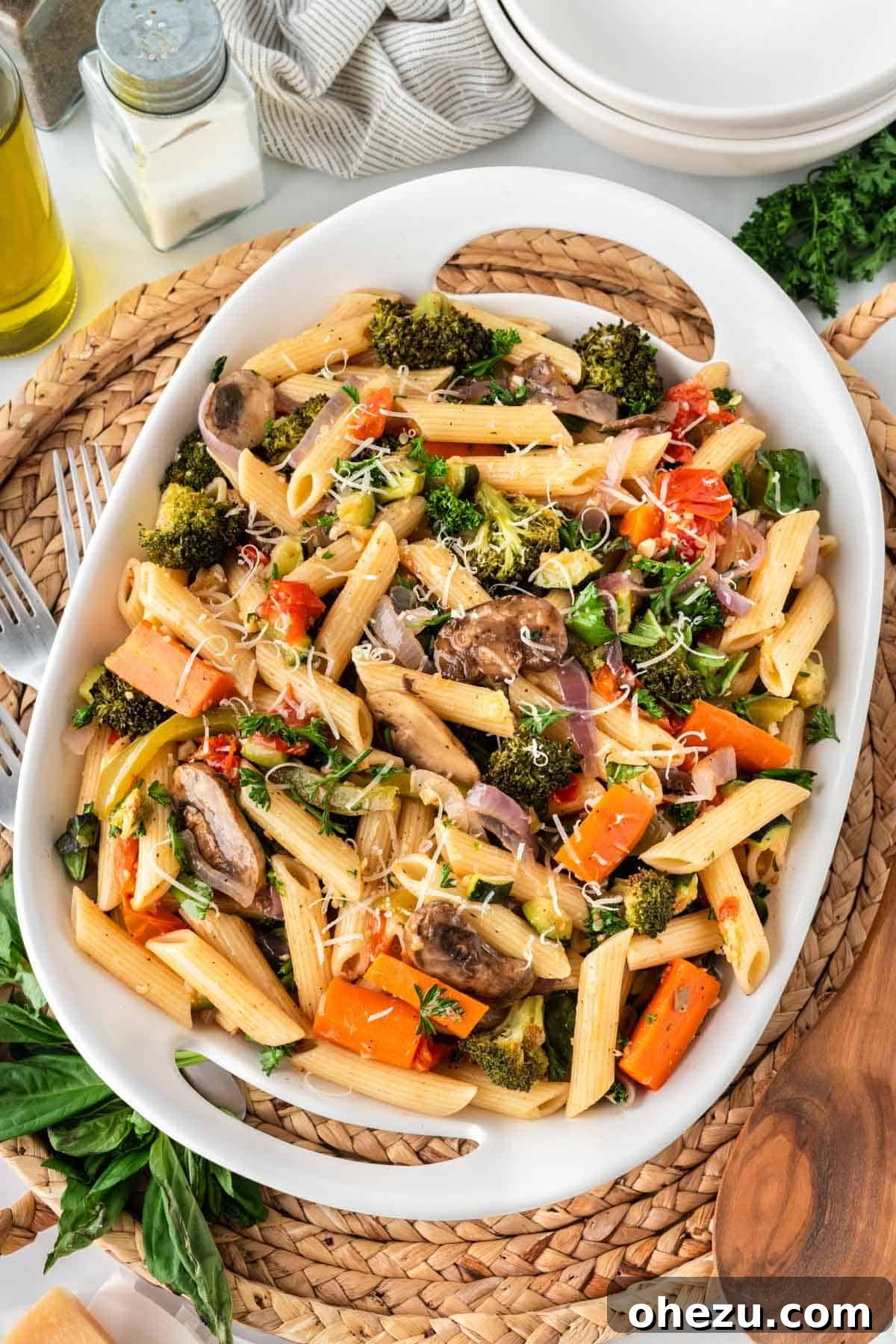 A large white serving dish filled with colorful roasted vegetable pasta, ready to be served.
