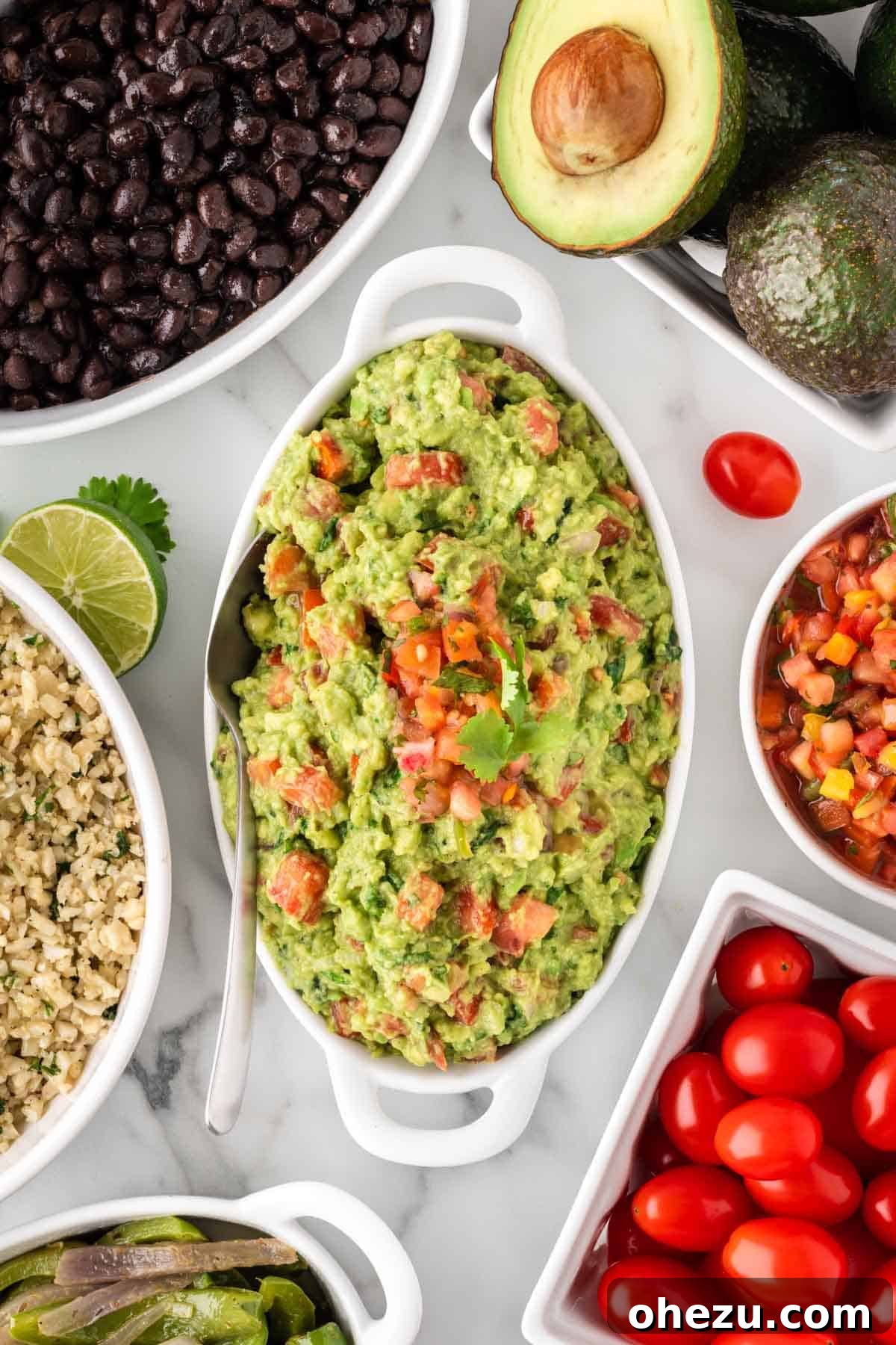 Freshly made guacamole in a rustic serving dish, ready to be added to the bowls.
