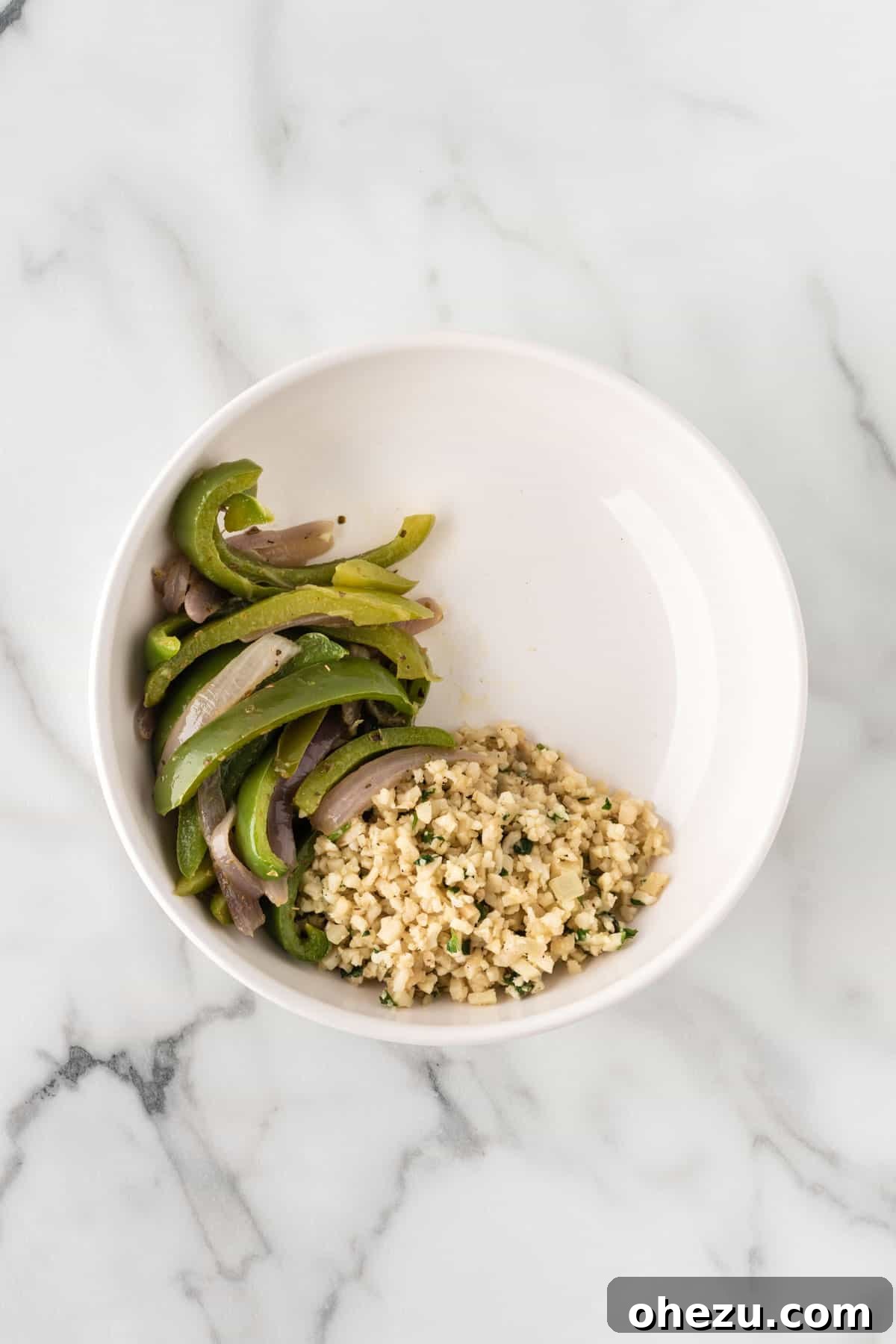 A bowl with cilantro lime cauliflower rice and fajita veggies already assembled.