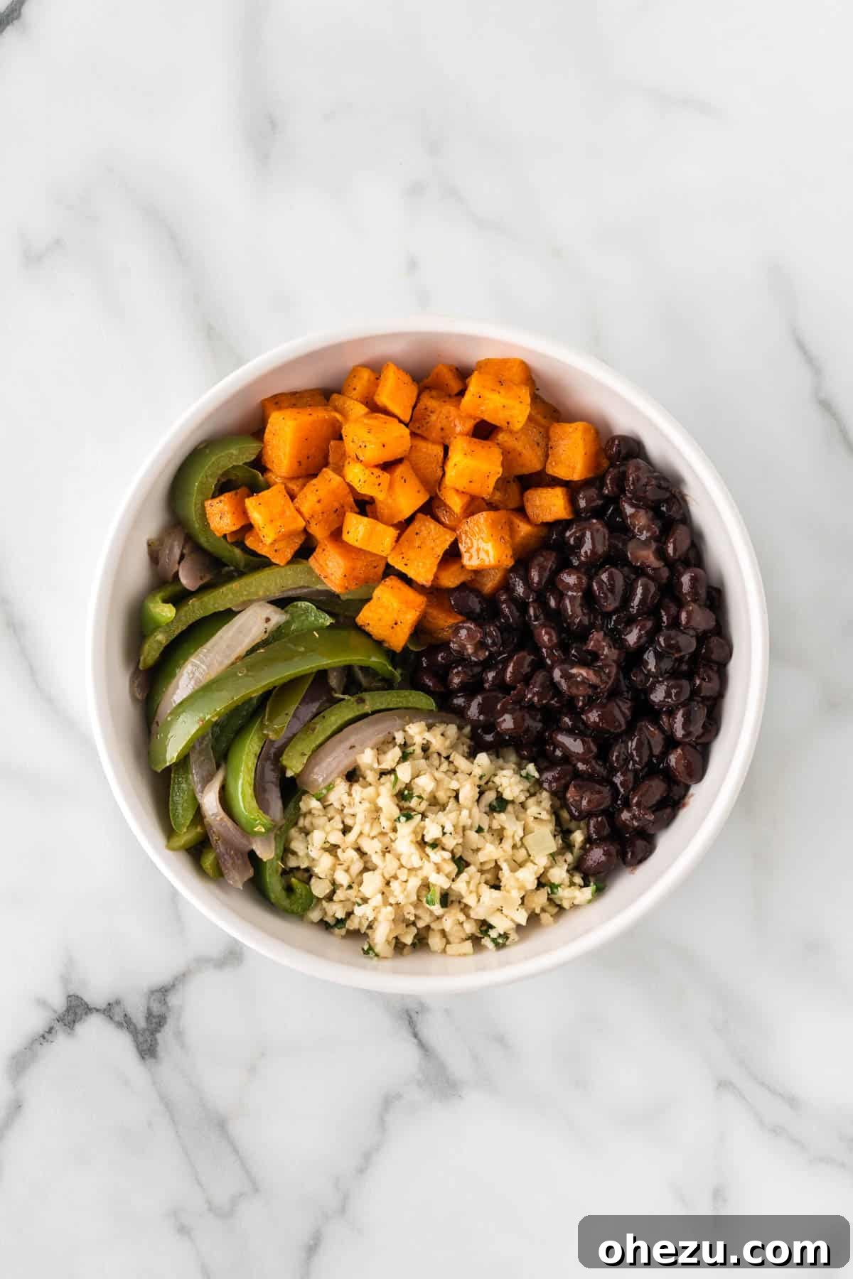 Adding roasted sweet potatoes and black beans to the burrito bowl.