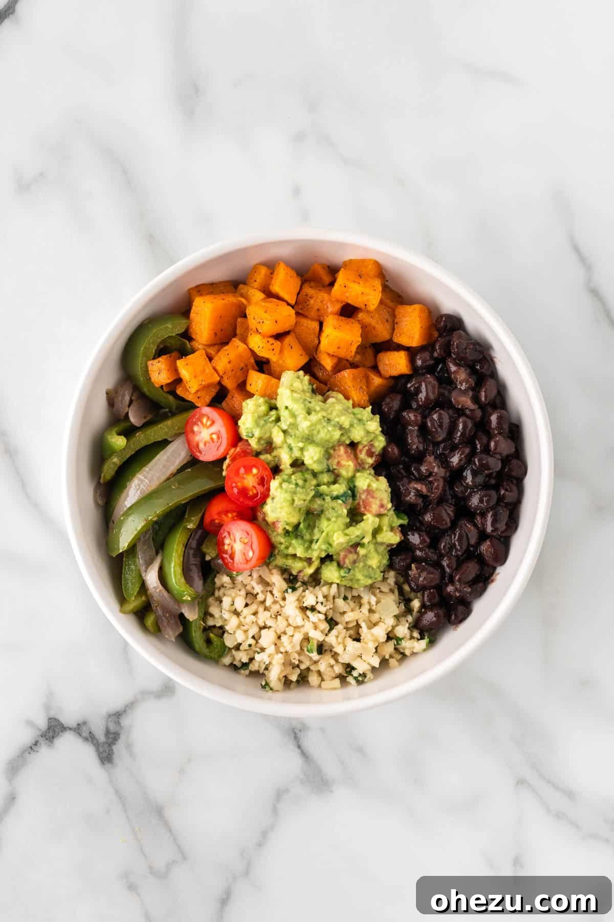 A generous scoop of guacamole being added to the finished burrito bowl.
