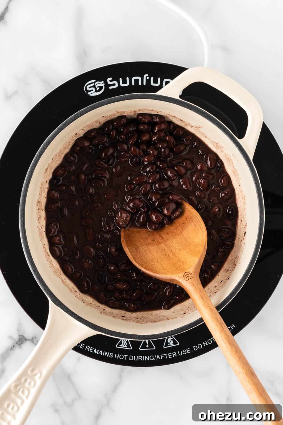 Stirring seasoned black beans in a saucepan.