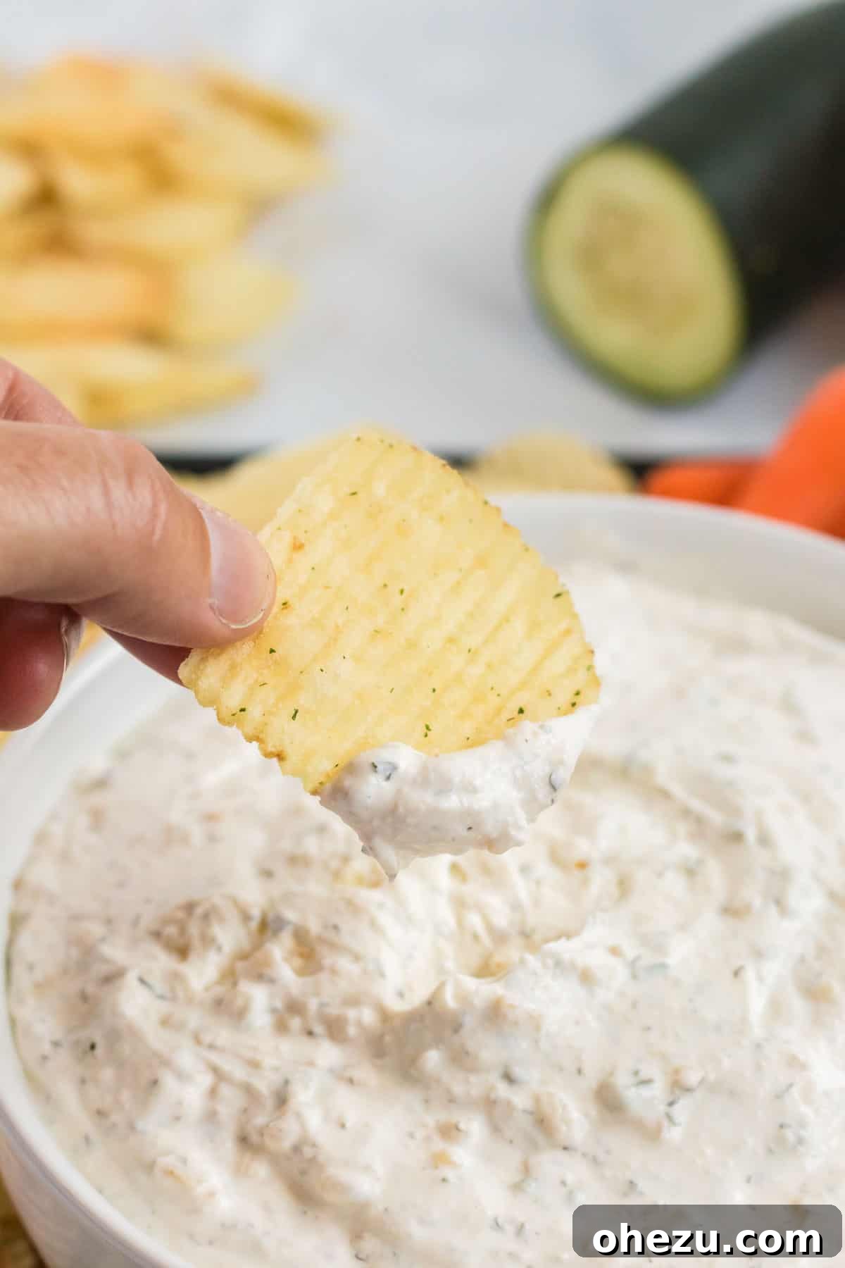 Crisp ruffle chip being perfectly dipped into a bowl of creamy homemade chip dip, highlighting its rich texture and inviting appeal.