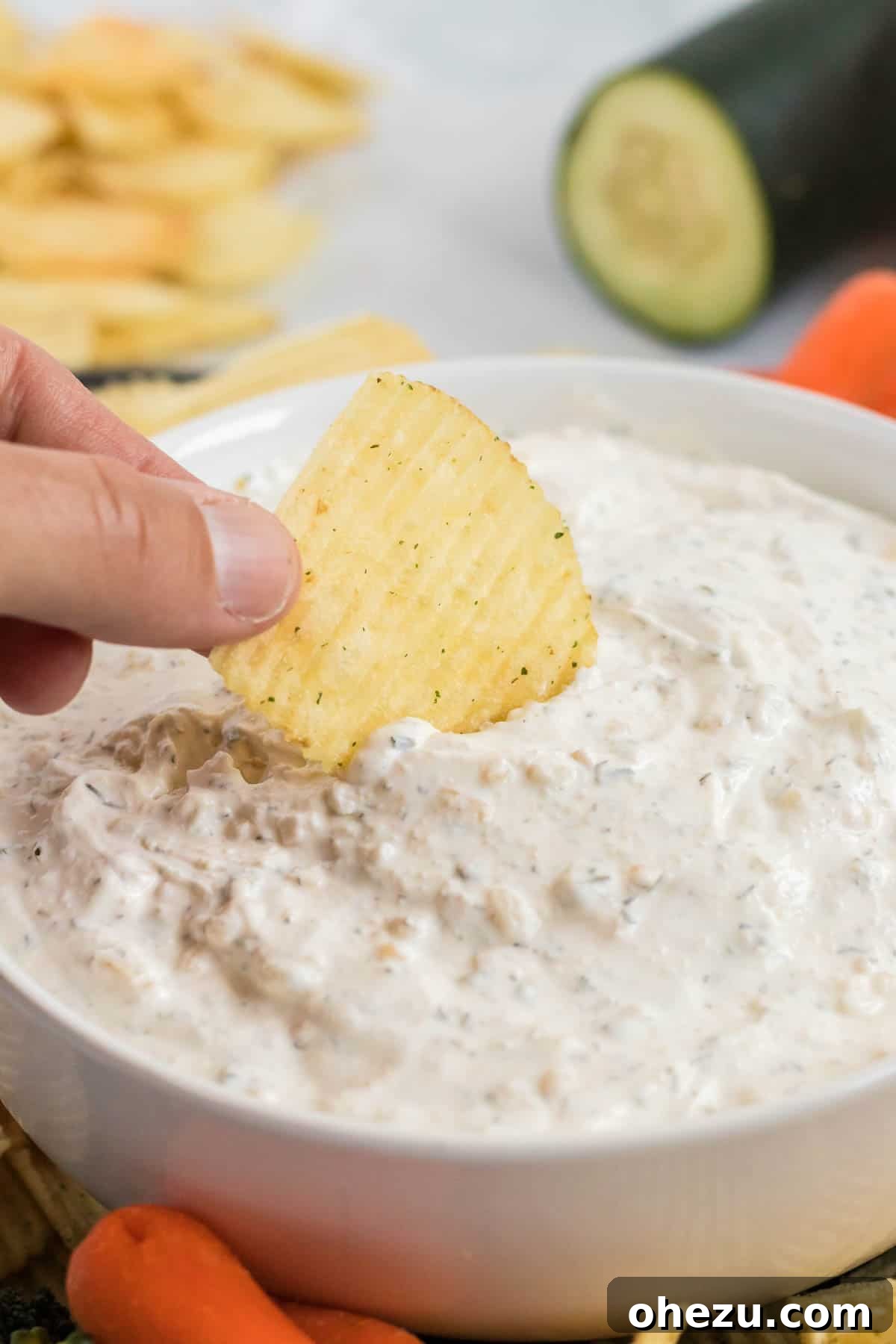 A chip fully submerged and loaded with creamy homemade dip, ready to be lifted and enjoyed, showcasing the generous texture of the dip.