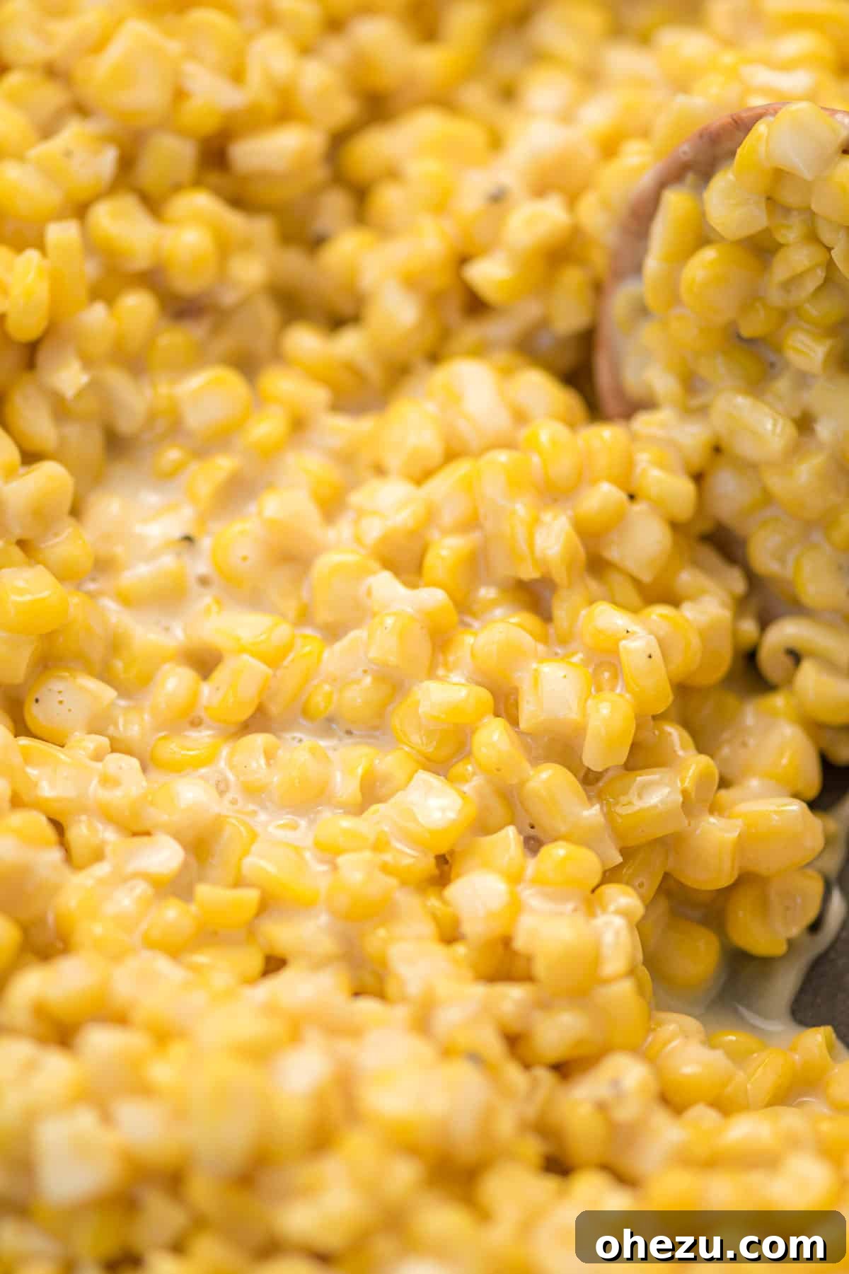 The simple ingredients for honey butter skillet corn laid out on a cutting board, including frozen corn, butter, honey, cream cheese, salt, and pepper.