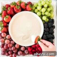 A tray full of mixed berries and grapes with a central bowl of creamy cream cheese fruit dip.