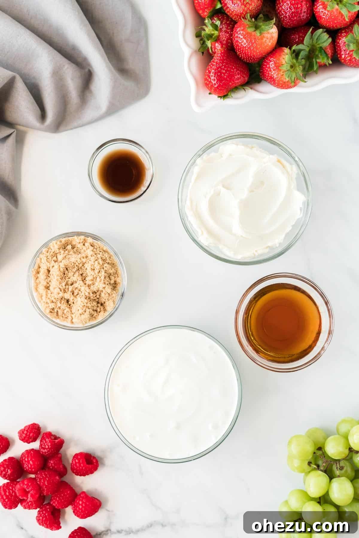 Individual glass bowls holding the five key ingredients for the cream cheese fruit dip: cream cheese, Greek yogurt, vanilla extract, maple syrup, and brown sugar.