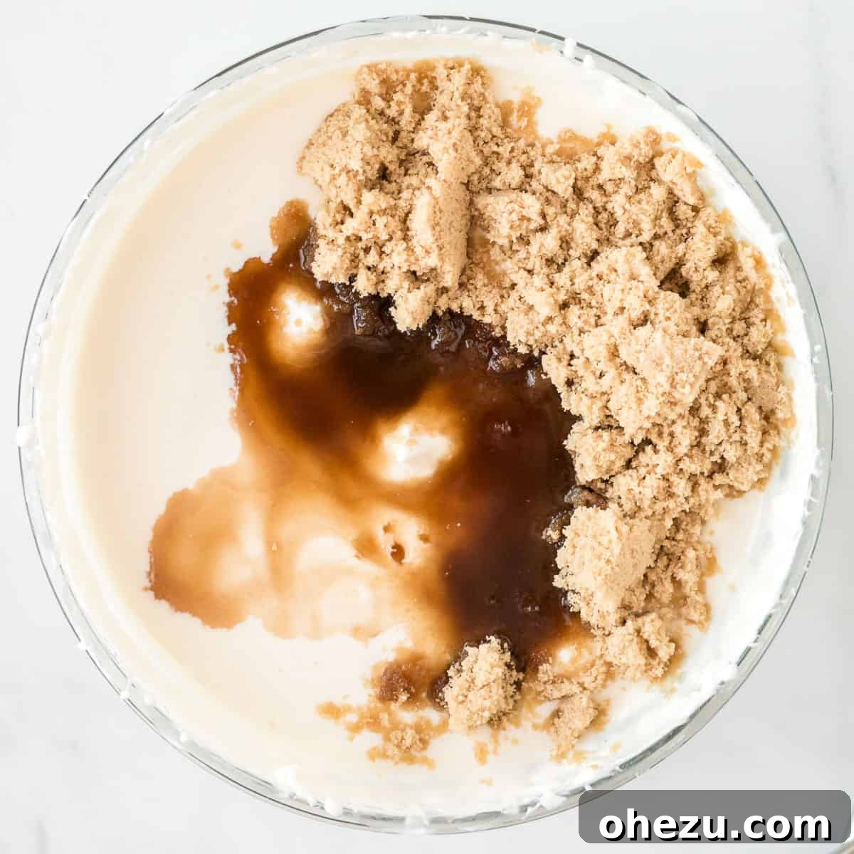 Close-up of brown sugar and vanilla extract being added to a creamy yogurt dip mixture in a bowl.