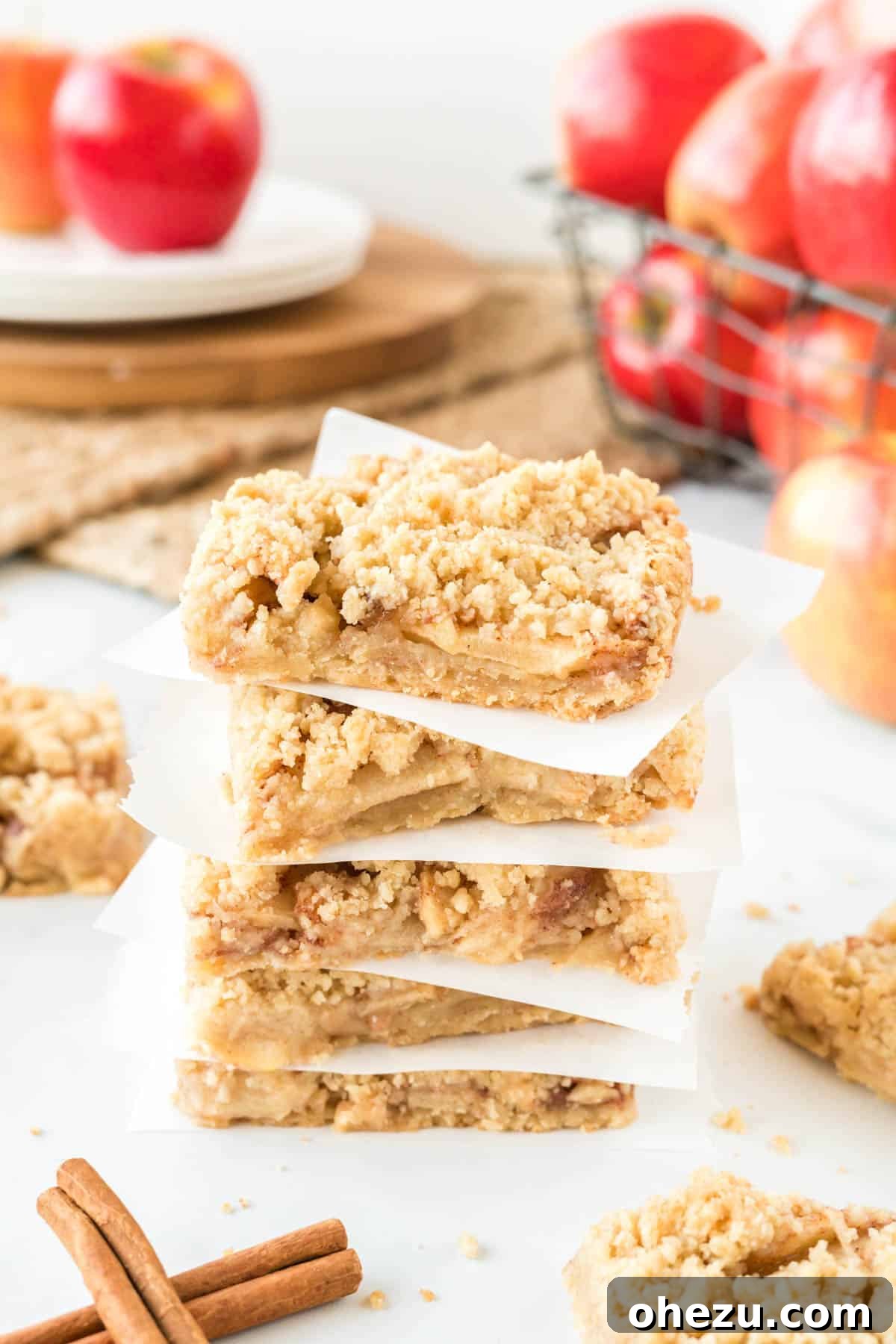 Beautifully stacked apple crisp bars with parchment paper in between, showing off the golden topping and crust