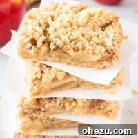 apple crisp bars stacked between squares of parchment paper - recipe card thumbnail