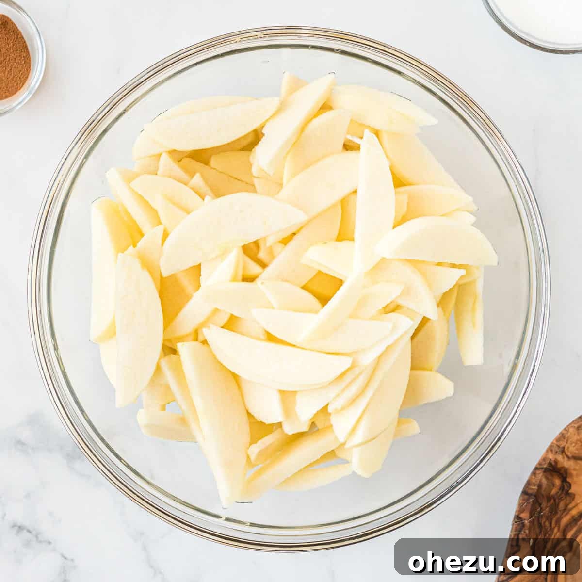 Thinly sliced apples in a clear glass bowl, ready for the crisp filling preparation
