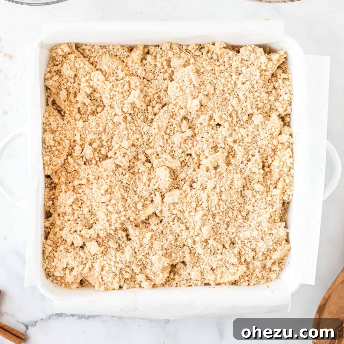 Crumb topping generously sprinkled over the apple filling in the baking pan, ready for final baking
