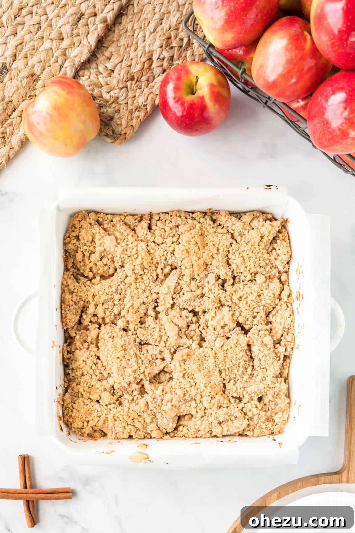 Baked apple crisp bars in a white square baking dish, cooling down on a counter