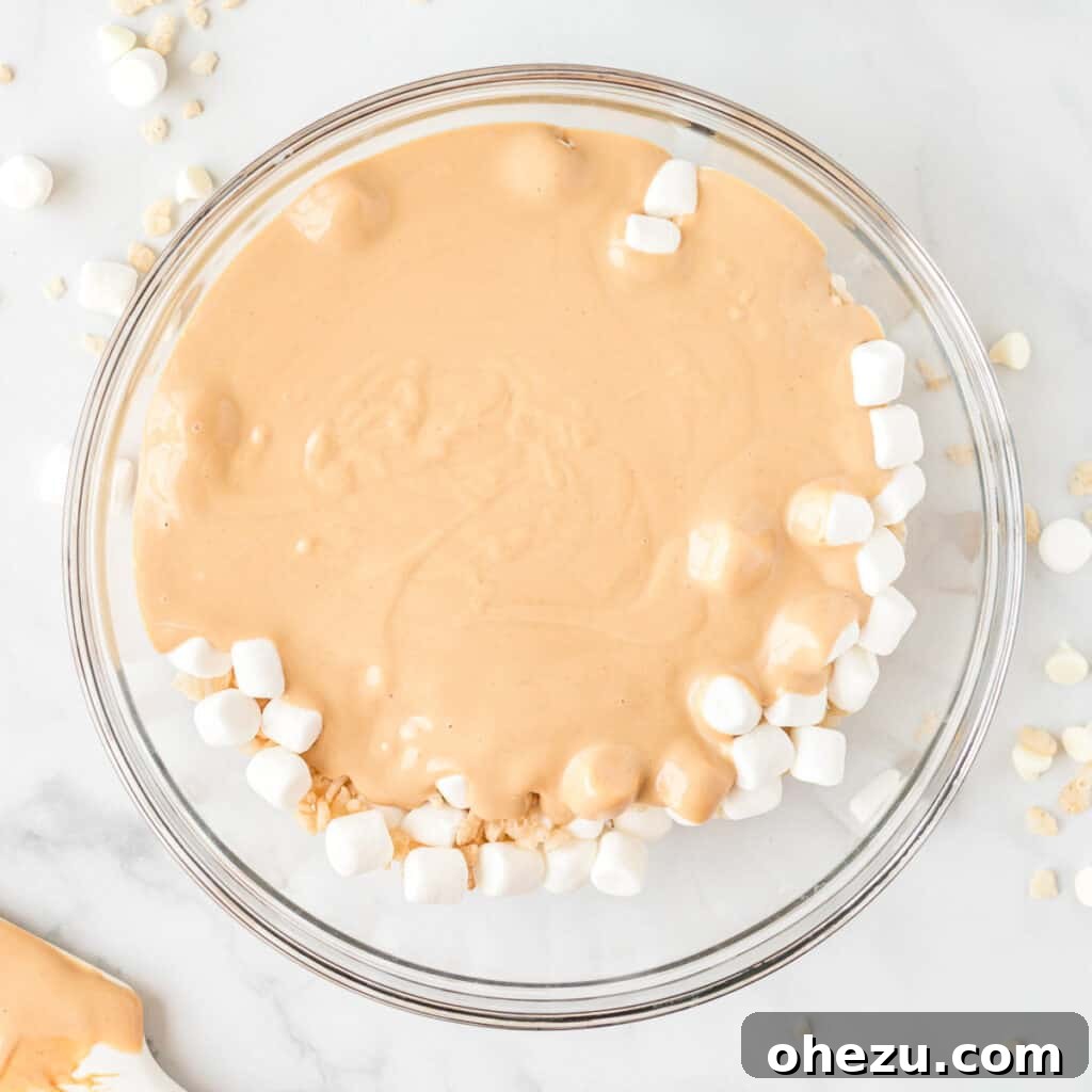 Kitchen Sink Cookies 9 Melted white chocolate and peanut butter being poured over the mixture of mini marshmallows and crisp rice cereal