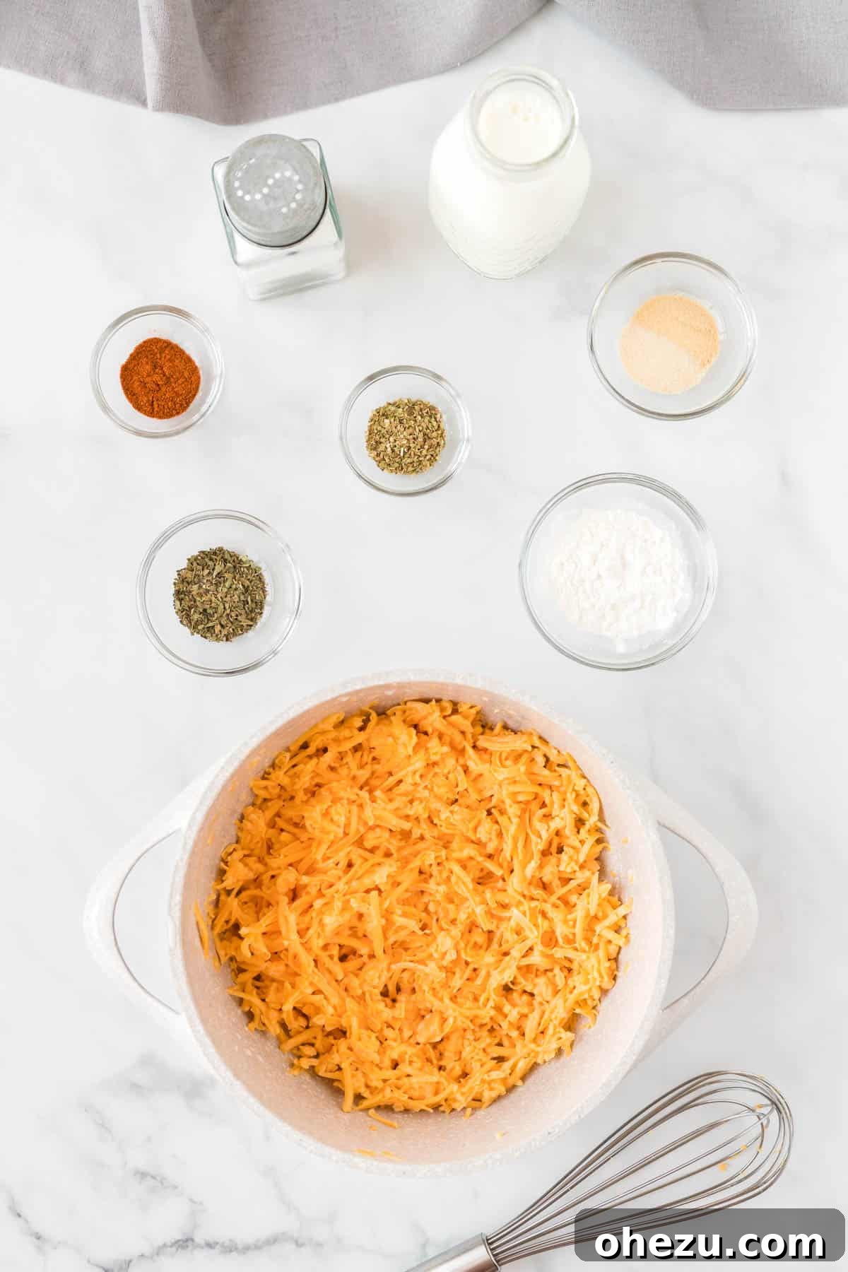 A saucepan filled with milk, shredded cheddar cheese, cornstarch, and various spices, being stirred to create the homemade cheese sauce.