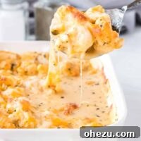 A spoon scooping cheesy cauliflower from the dish, demonstrating its creamy texture.