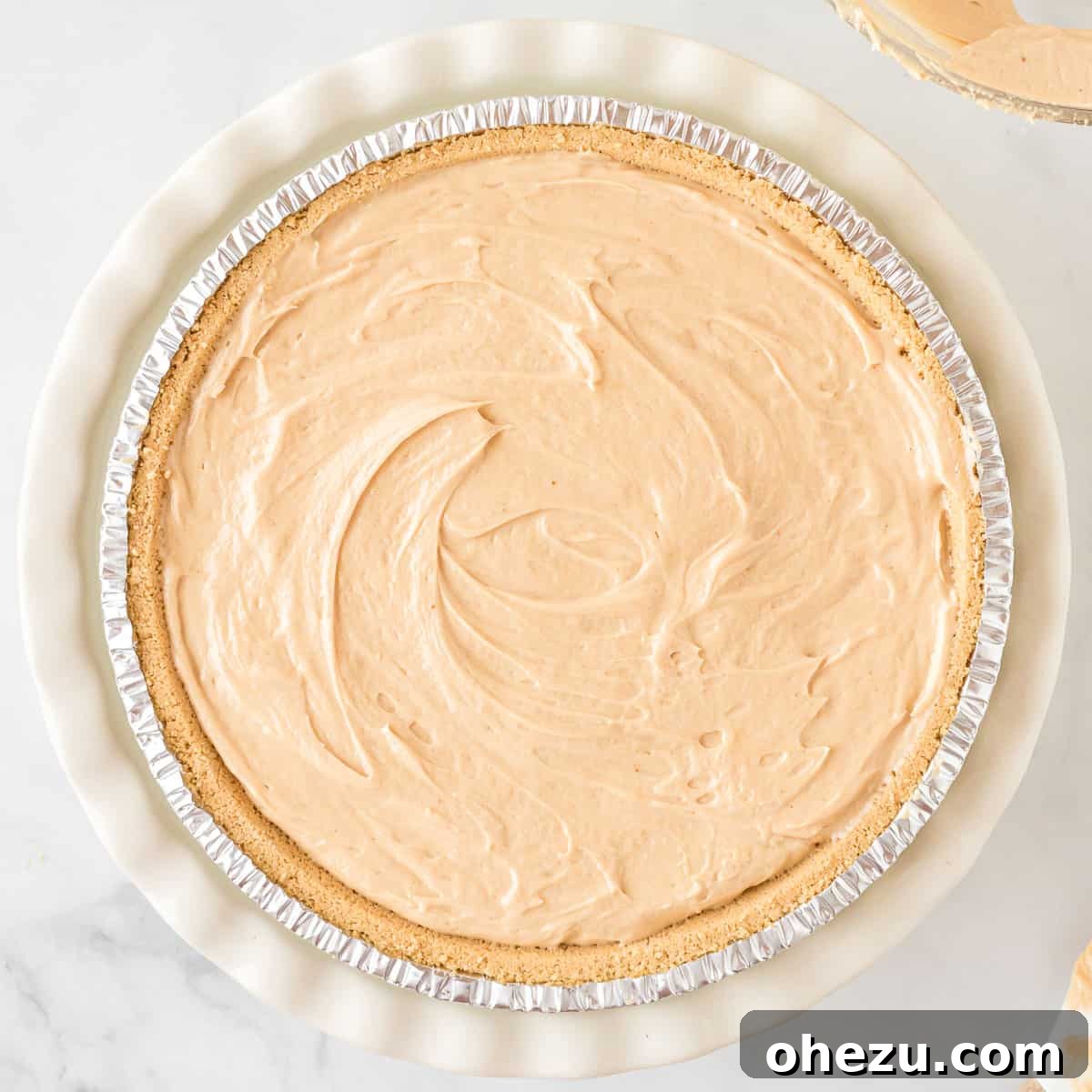 The no bake peanut butter pie filling neatly spread and smoothed into the graham cracker crust, showcasing a perfect, even surface ready for chilling.