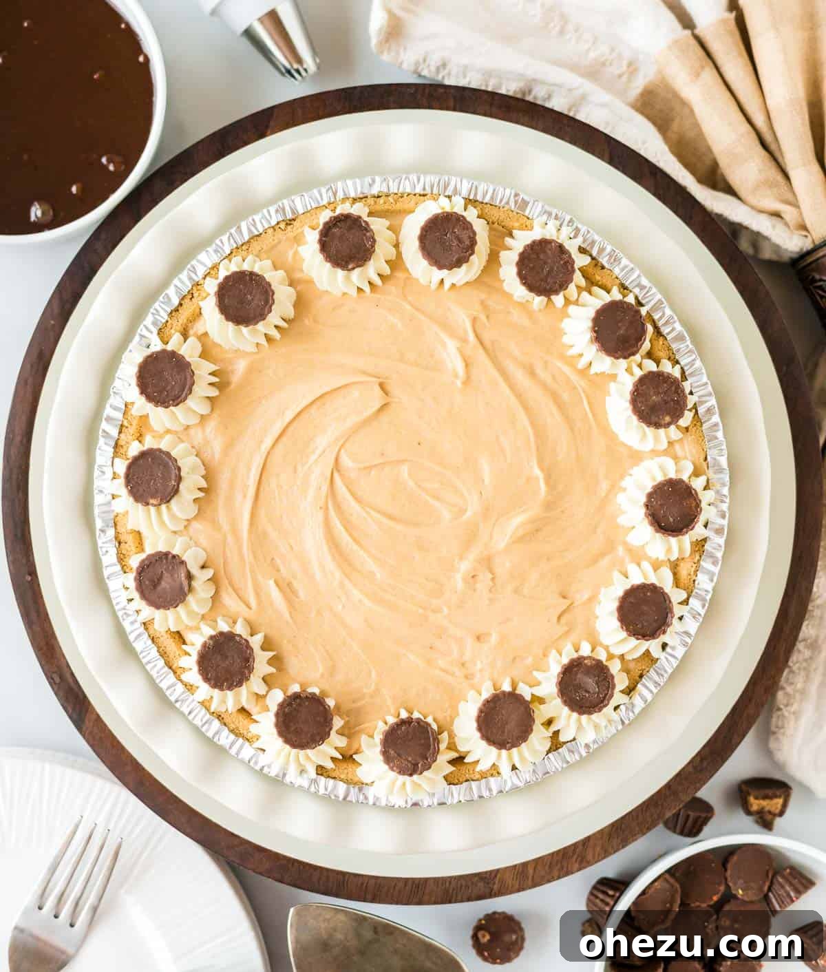 The chilled no bake peanut butter pie, beautifully decorated with artistic swirls of whipped cream and generously topped with mini Reese's cups, ready for serving.