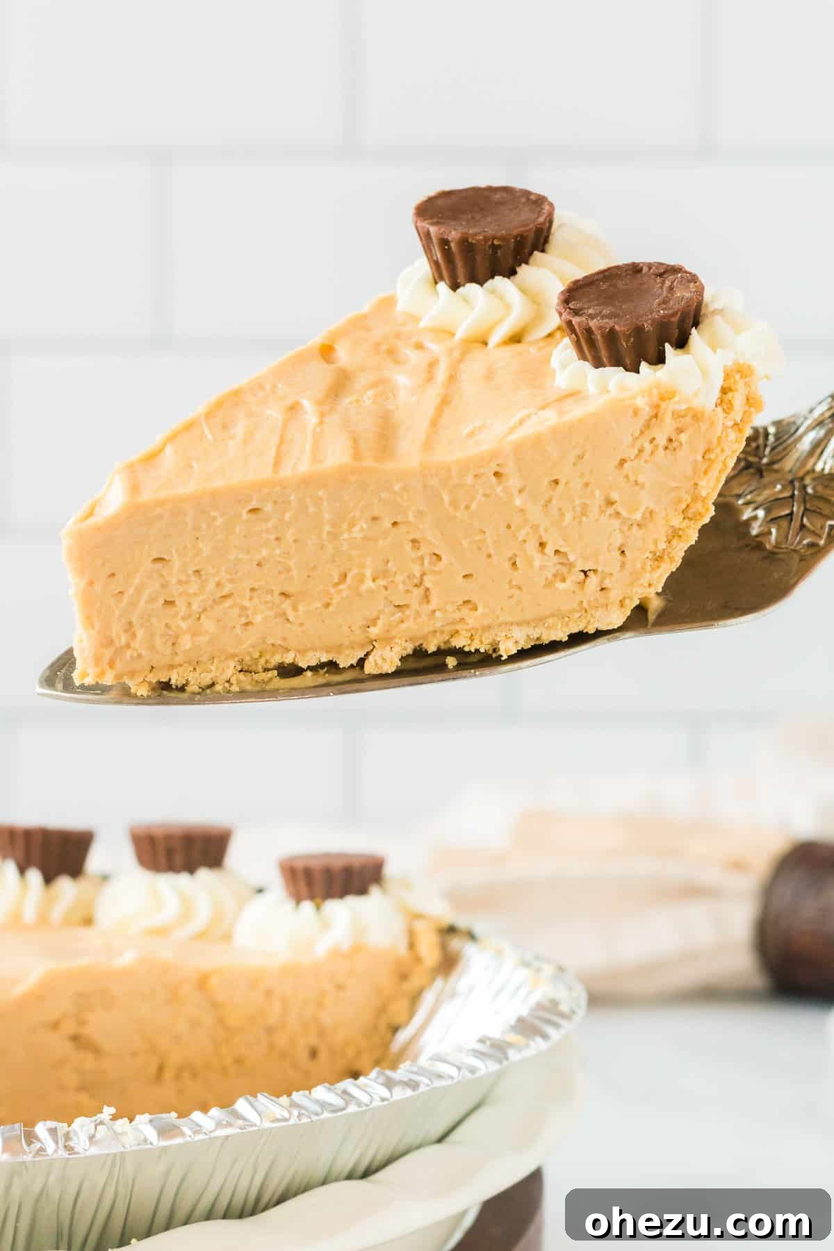 A hand expertly taking a perfect, clean slice of the no bake peanut butter pie from the dish, clearly showing its firm, smooth, and creamy texture.