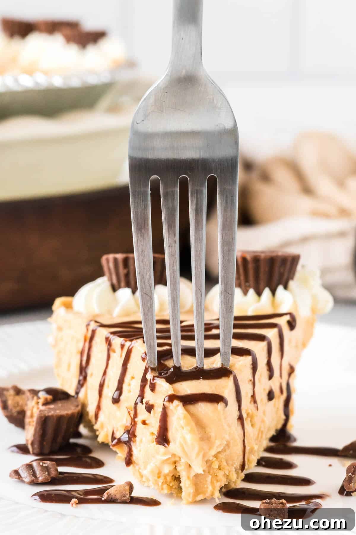 A person taking a delicious bite out of a slice of no bake peanut butter pie, beautifully drizzled with rich chocolate sauce.