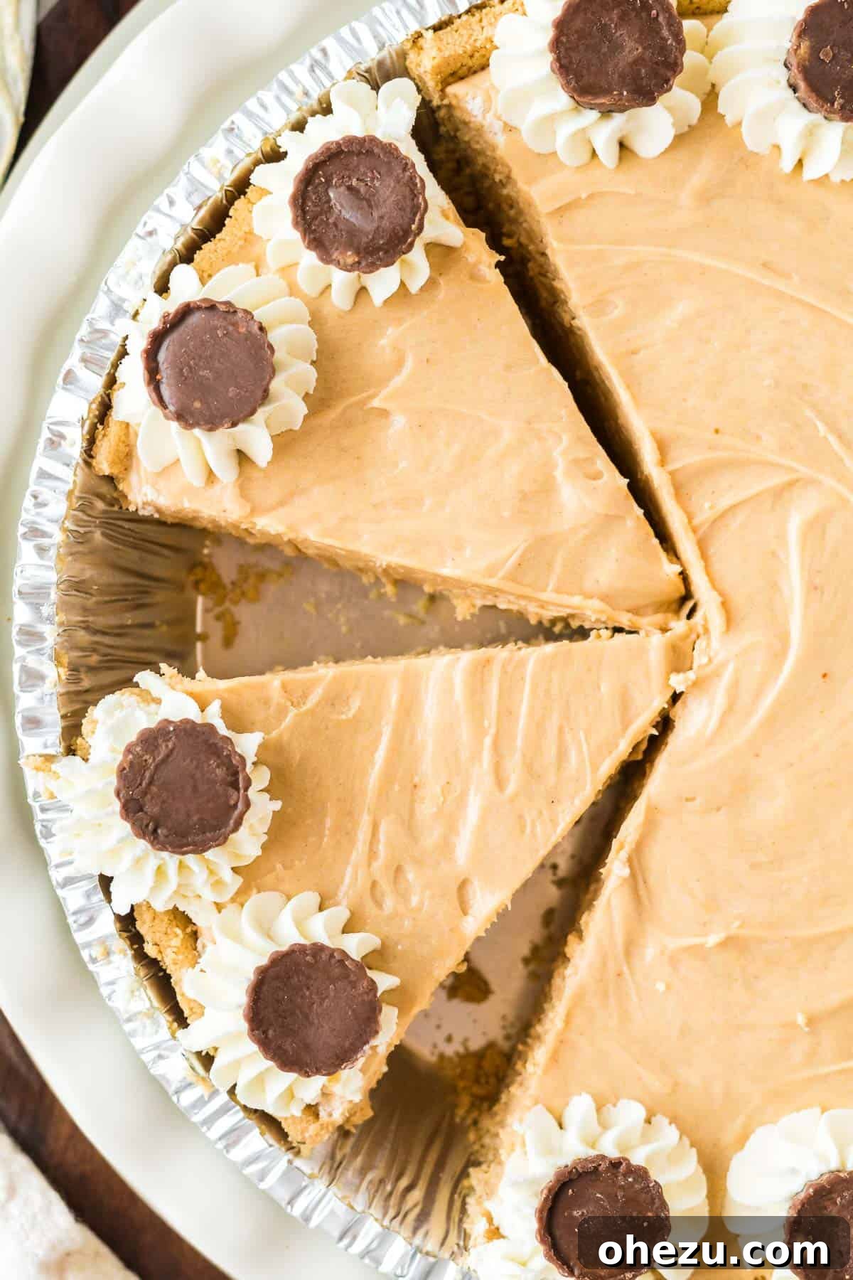 A whole no bake peanut butter pie, perfectly and cleanly cut into several individual slices, showcasing its smooth, creamy interior and crisp graham cracker crust.