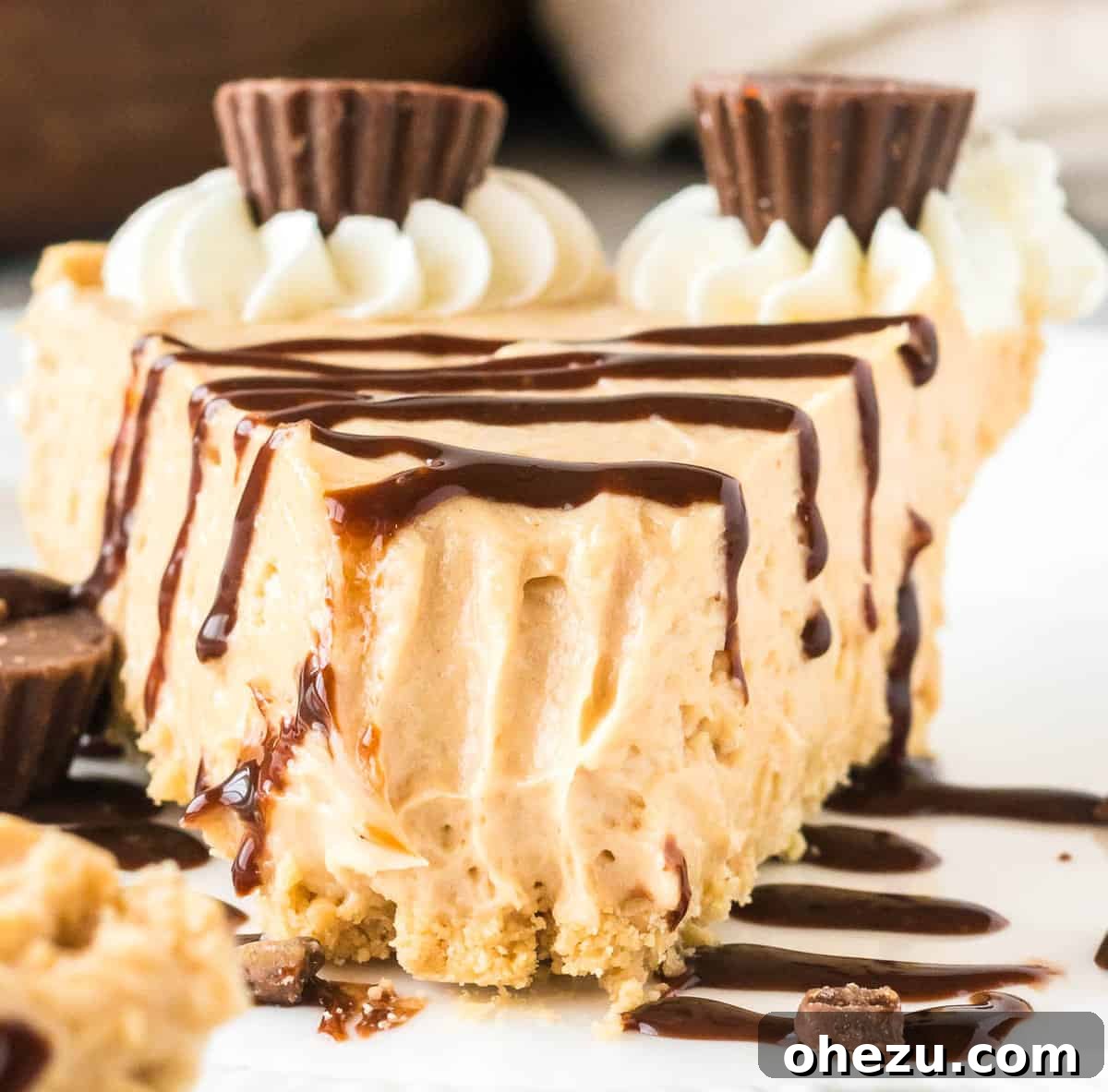 A close-up of a delectable slice of no bake peanut butter pie, artfully drizzled with chocolate sauce, with a small bite elegantly taken out, perfectly revealing its rich, creamy texture and inviting appeal.