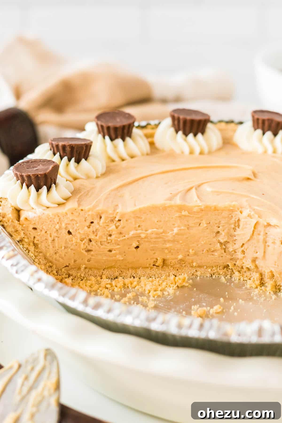 The full no bake peanut butter pie, set and ready to be sliced, showcasing its smooth, creamy surface in a golden graham cracker crust.