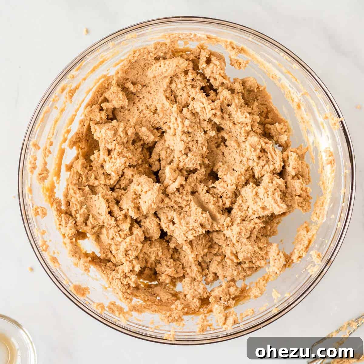 Smooth and well-combined mixture of cream cheese and peanut butter in a mixing bowl, after being beaten together to a uniform consistency.
