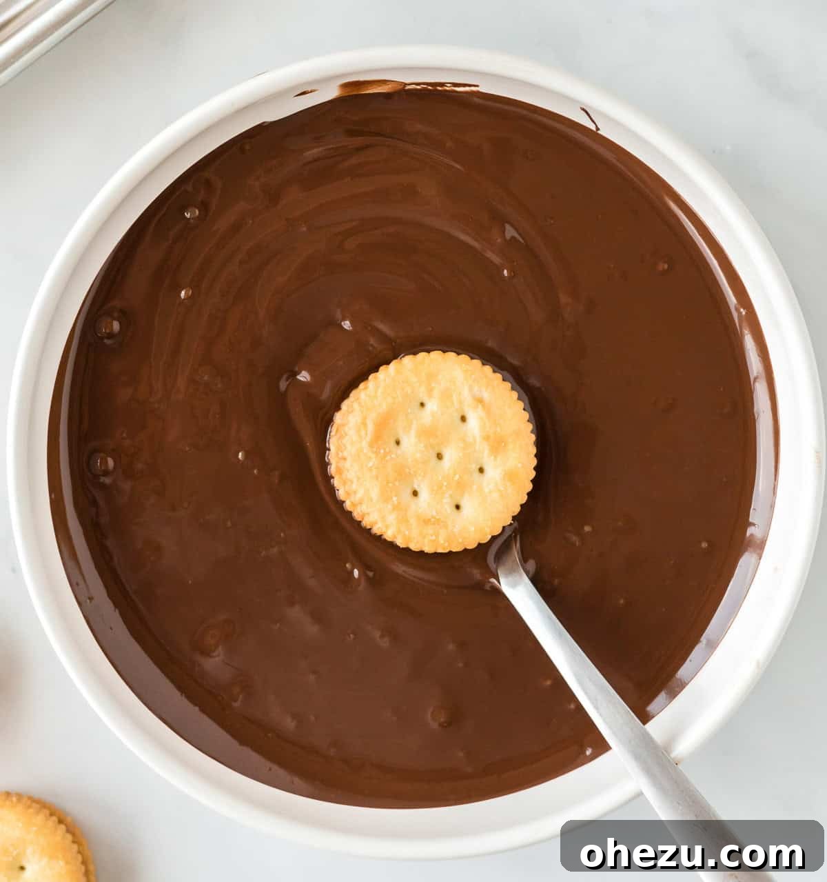 Dipping a Ritz cracker cookie into a bowl of melted chocolate