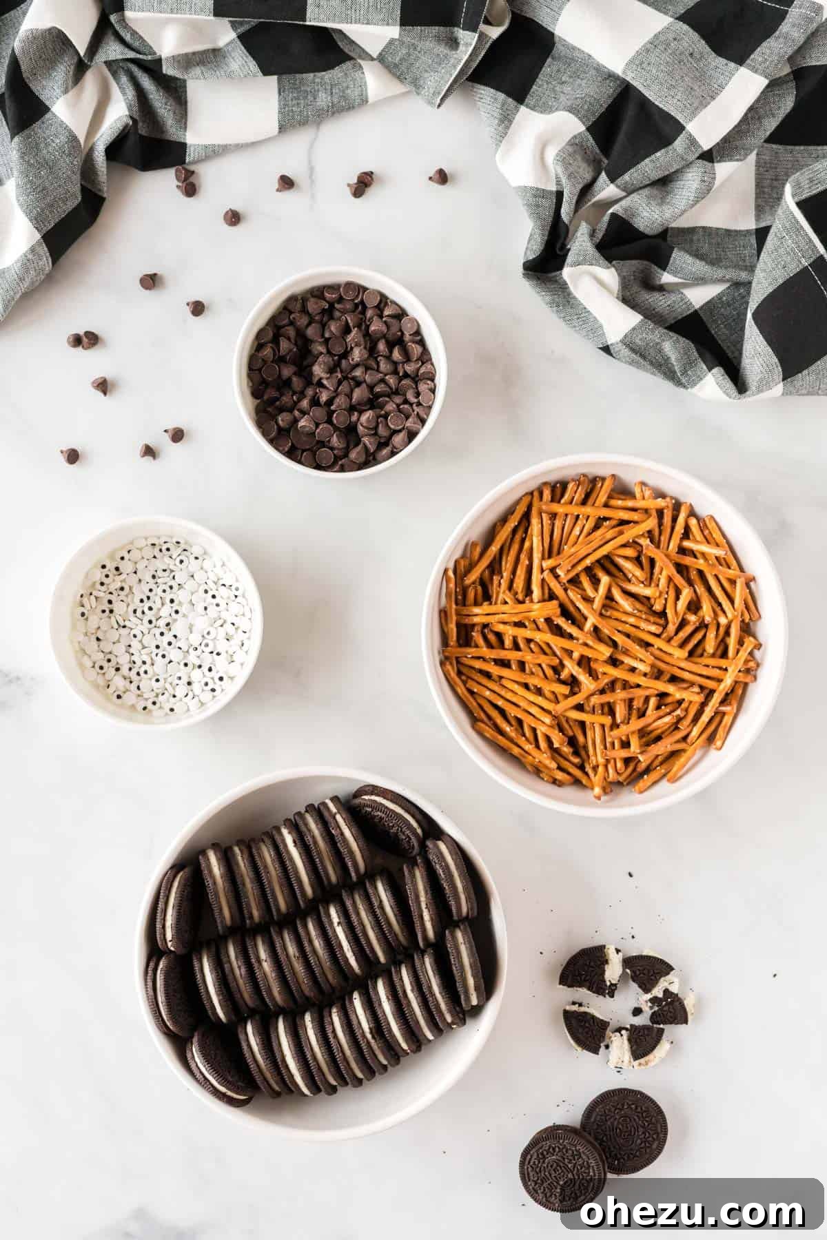 Spooky Oreo Spiders 4 All ingredients laid out: a pack of Oreos, a bag of chocolate chips, a container of googly eye candies, and a bag of pretzel rods