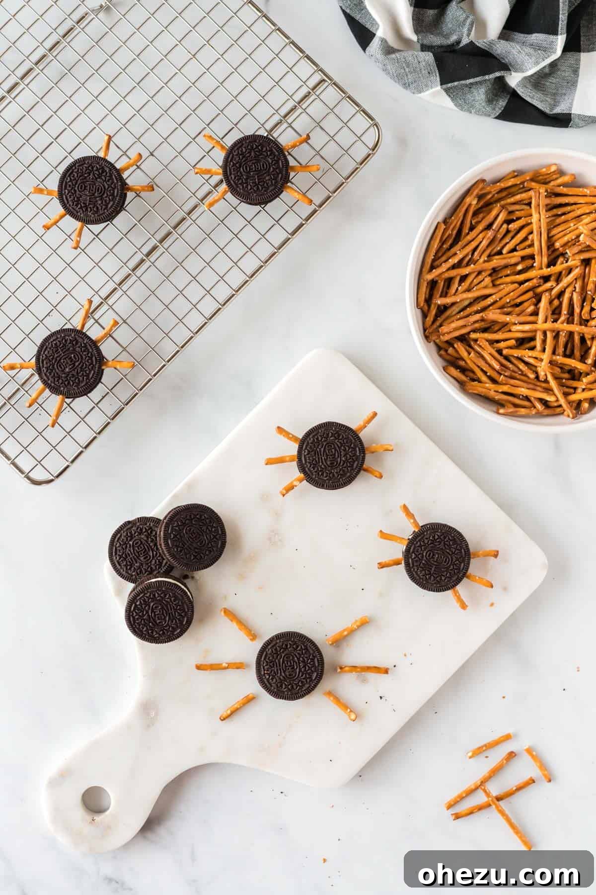 Spooky Oreo Spiders 5 A hand gently inserting a pretzel rod half into the cream filling of an Oreo cookie to form a spider leg