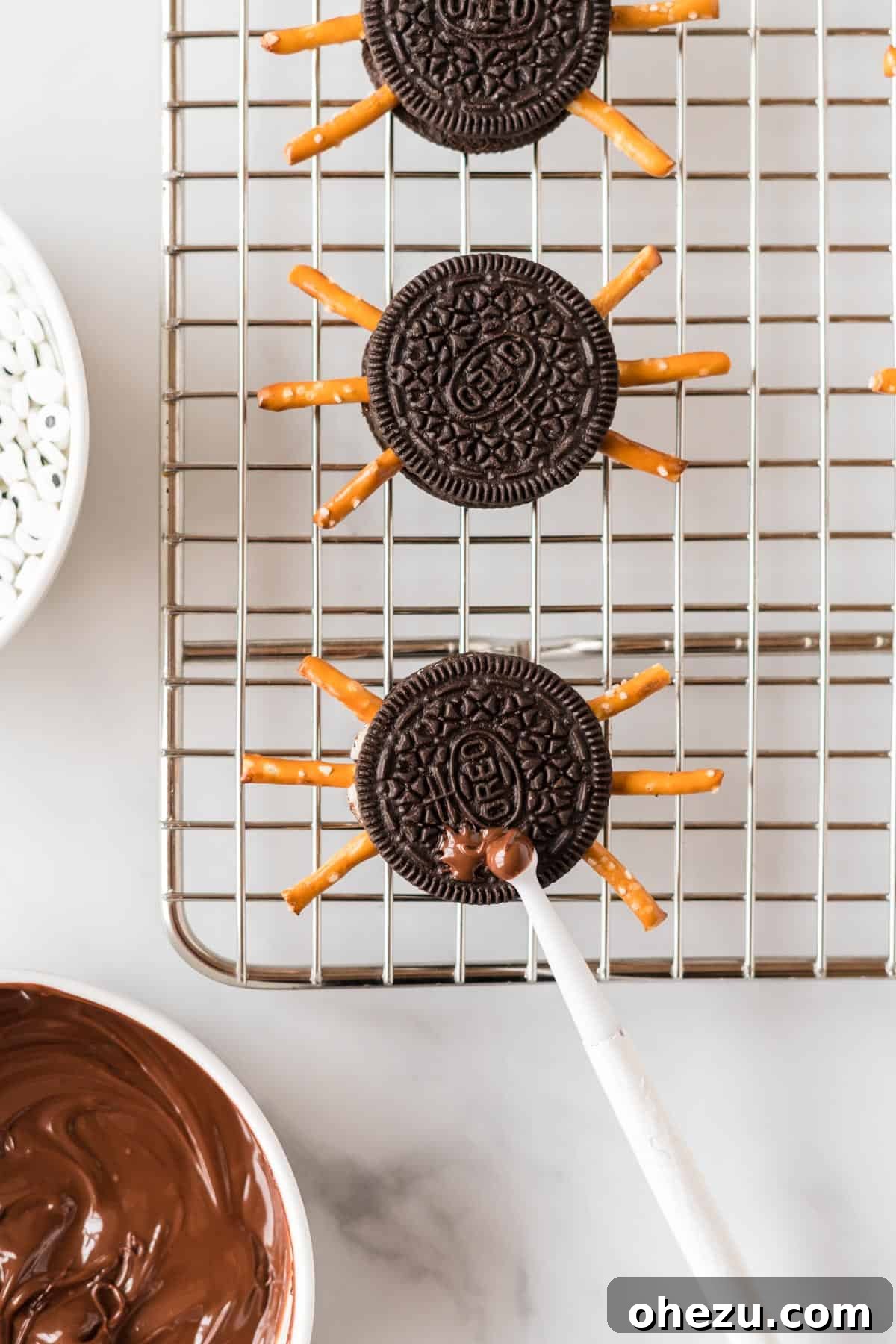 Spooky Oreo Spiders 9 A toothpick applying a dot of melted chocolate to an Oreo cookie to attach a googly eye