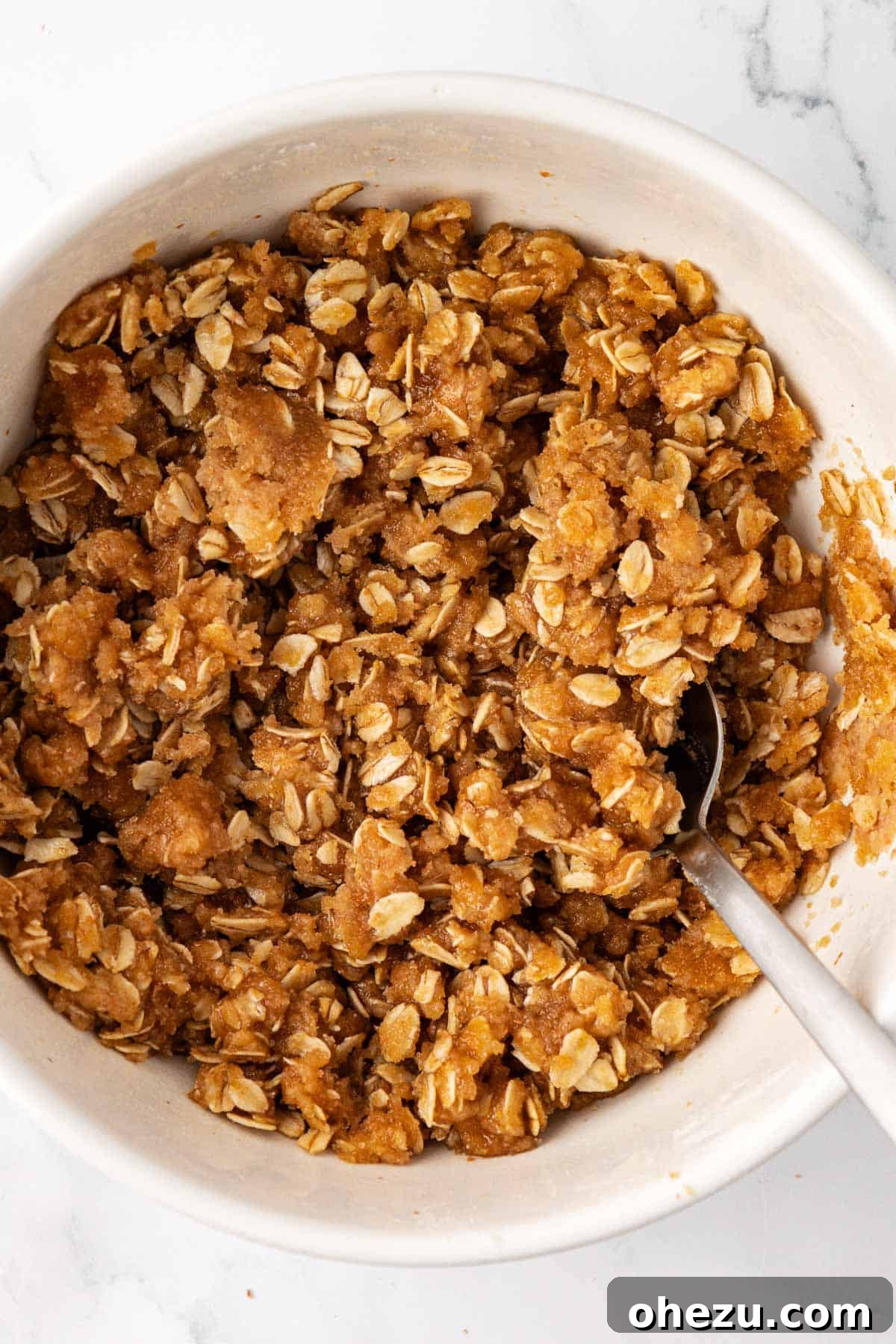 The vegan apple crisp topping mixed together in a bowl, showing a crumbly, wet sand-like texture.
