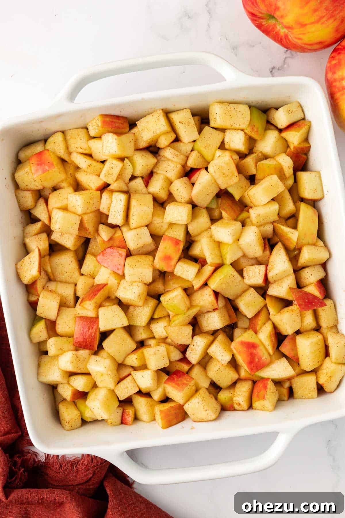 Spiced apple filling neatly arranged in a greased baking dish, ready for the topping.