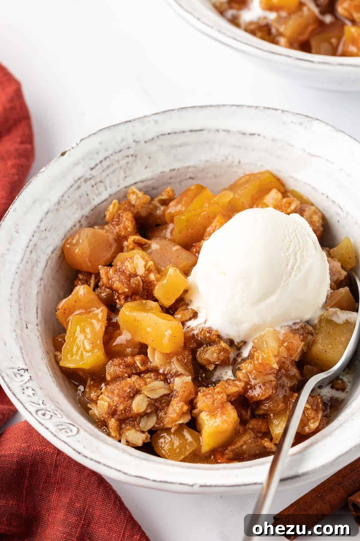 Another enticing view of vegan apple crisp with a scoop of ice cream, showing the rich texture of the topping and filling.