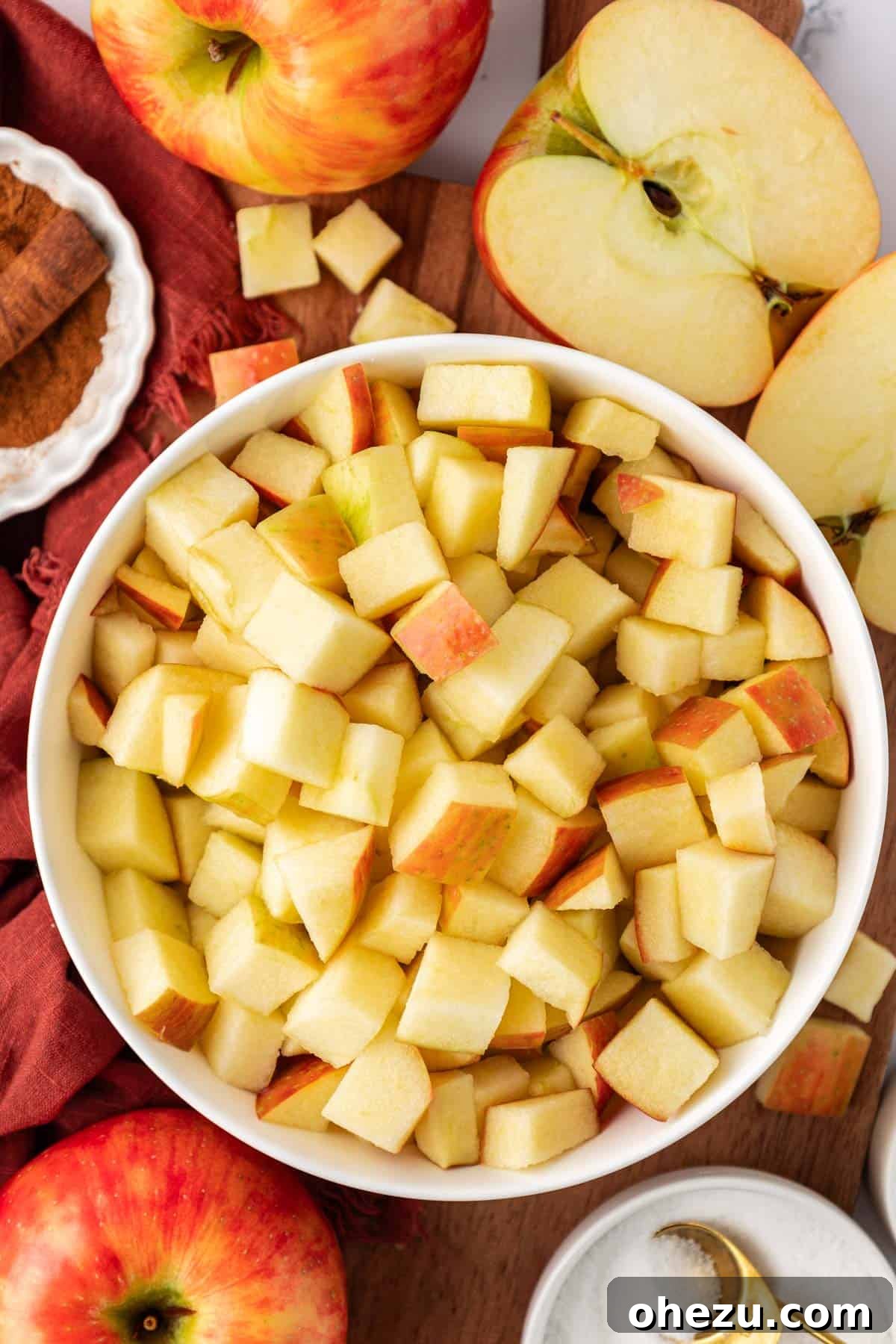 Freshly diced apples in a large mixing bowl, ready for the filling ingredients.