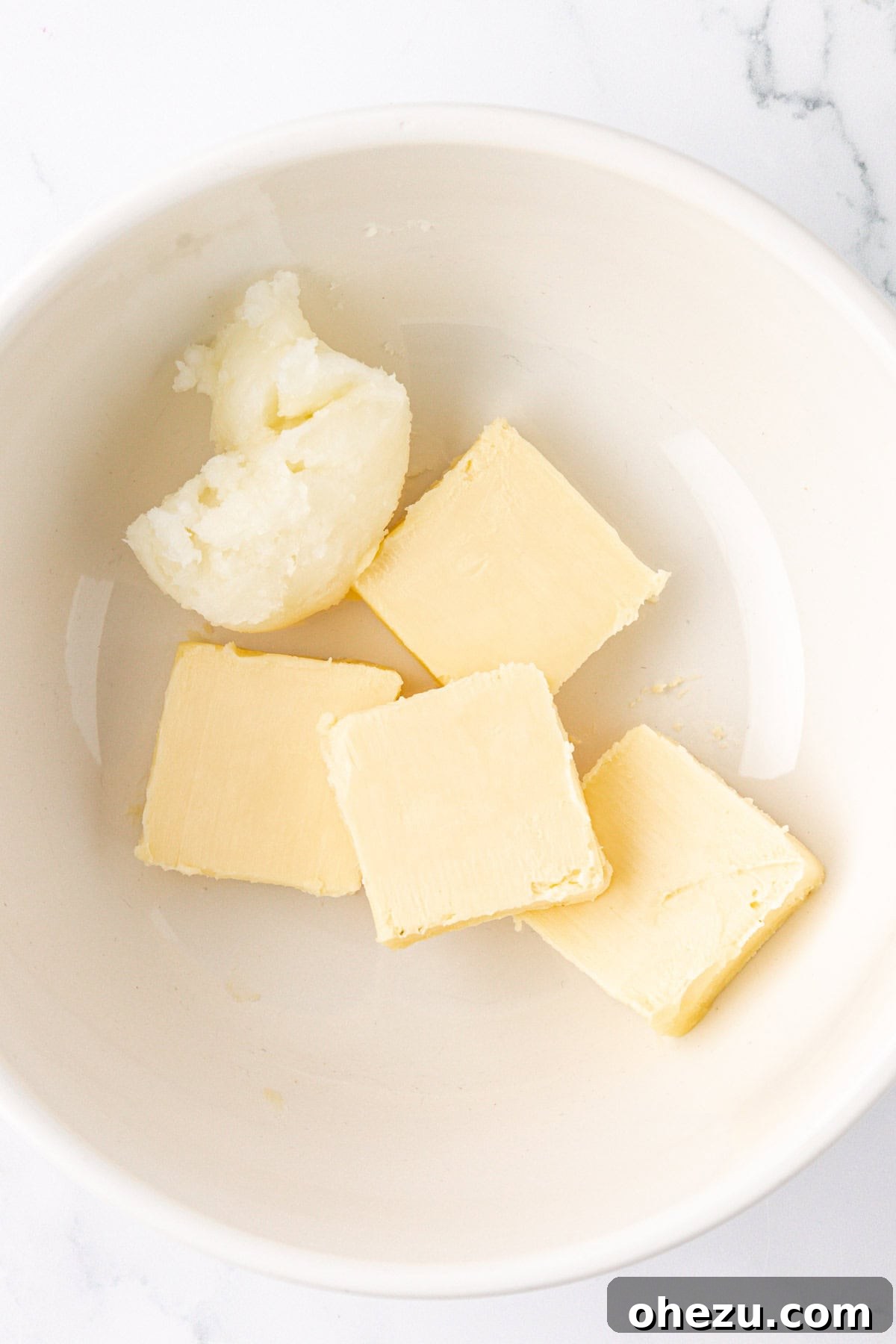 Solid vegan butter and coconut oil in a microwave-safe bowl before melting.