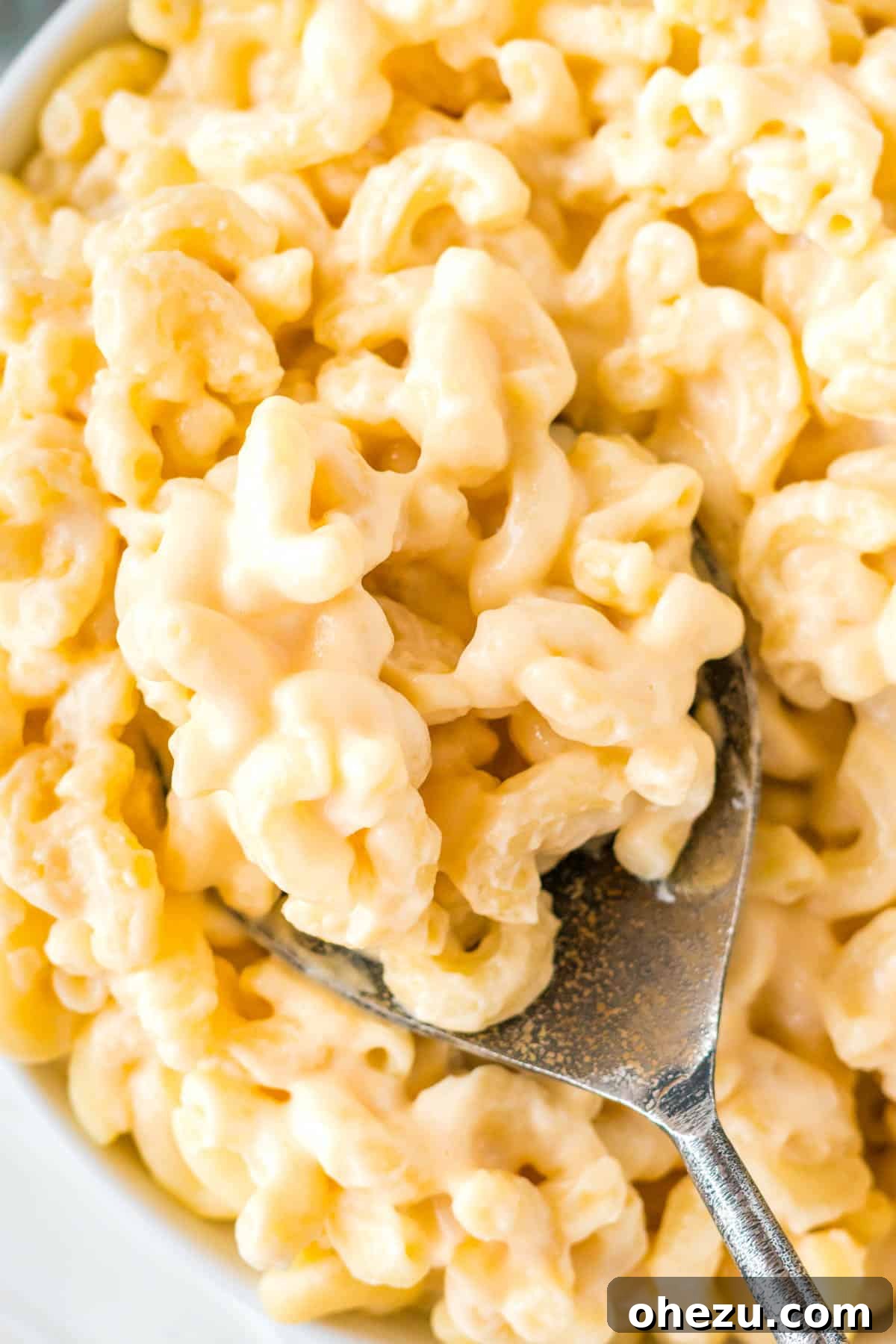 Tangy Greek Yogurt Mac and Cheese 10 serving spoon taking a scoop of mac and cheese