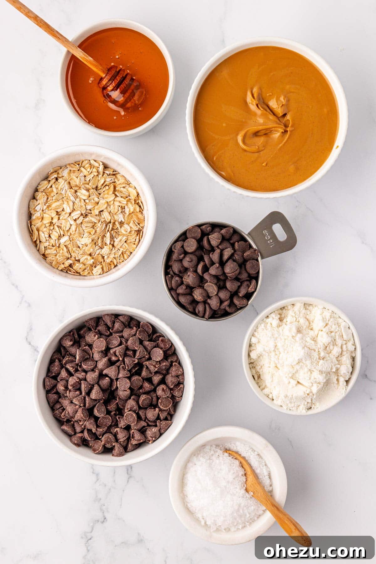 Ingredients laid out for making no bake protein bars: peanut butter, honey, oats, protein powder, chocolate chips, and sea salt