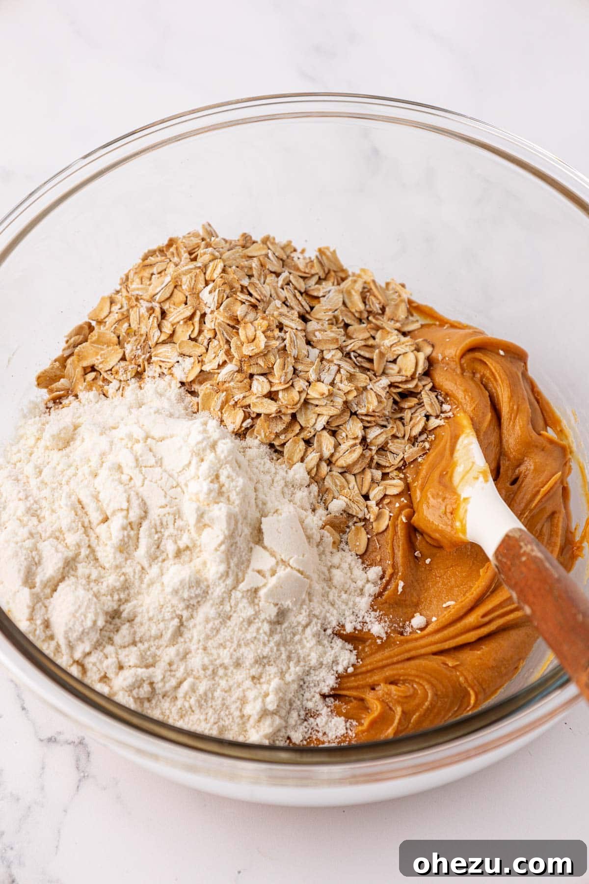 Adding rolled oats and vanilla protein powder to the peanut butter and honey mixture