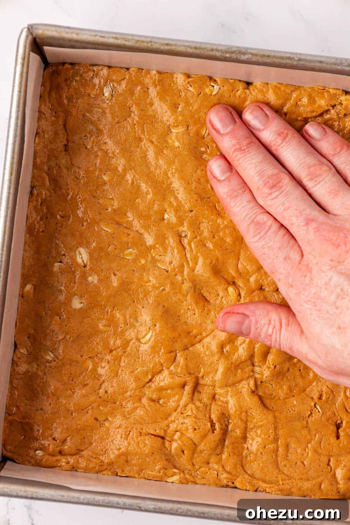 Pressing the protein bar batter firmly into a parchment-lined pan