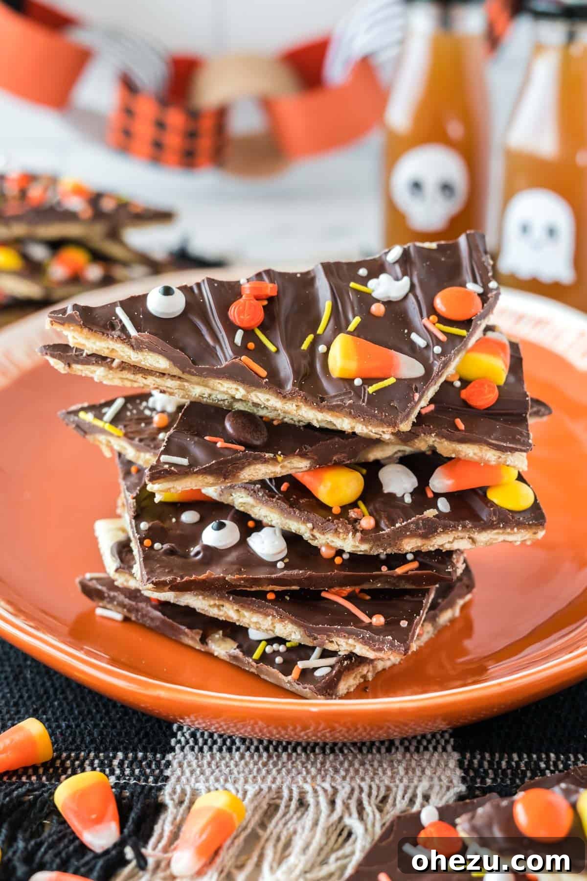 Stacked pieces of delicious Halloween crack candy on an vibrant orange plate, ready to be served at a spooky gathering.