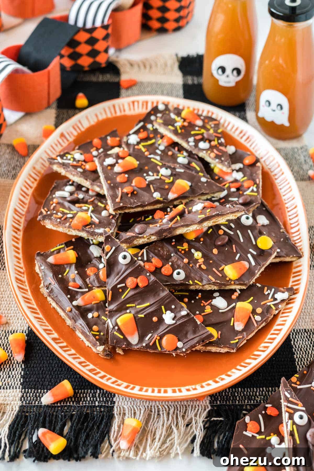 An orange serving plate piled high with vibrant, decorated Halloween crack candy pieces, perfect for a festive display.