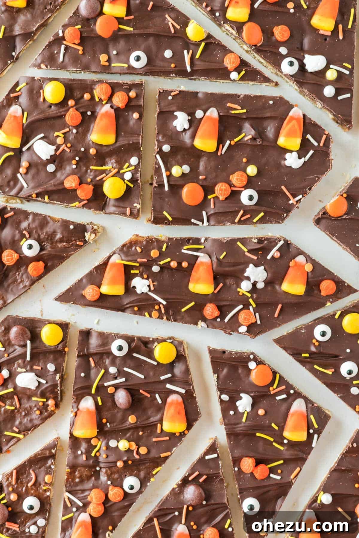 Multiple pieces of broken Halloween crack candy, highlighting the various toppings and textures, signifying a delicious batch.